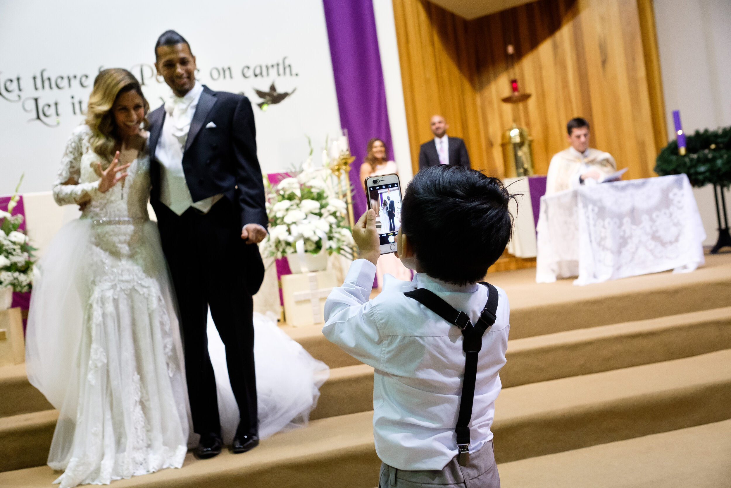  One of the ring bearers takes a picture of Anita + Gehan during their church wedding ceremony before their  wedding reception  at Angus Glenn just outside of Toronto, Ontario. Wedding photograph by Scott Williams (www.scottwilliamsphotographer.com) 