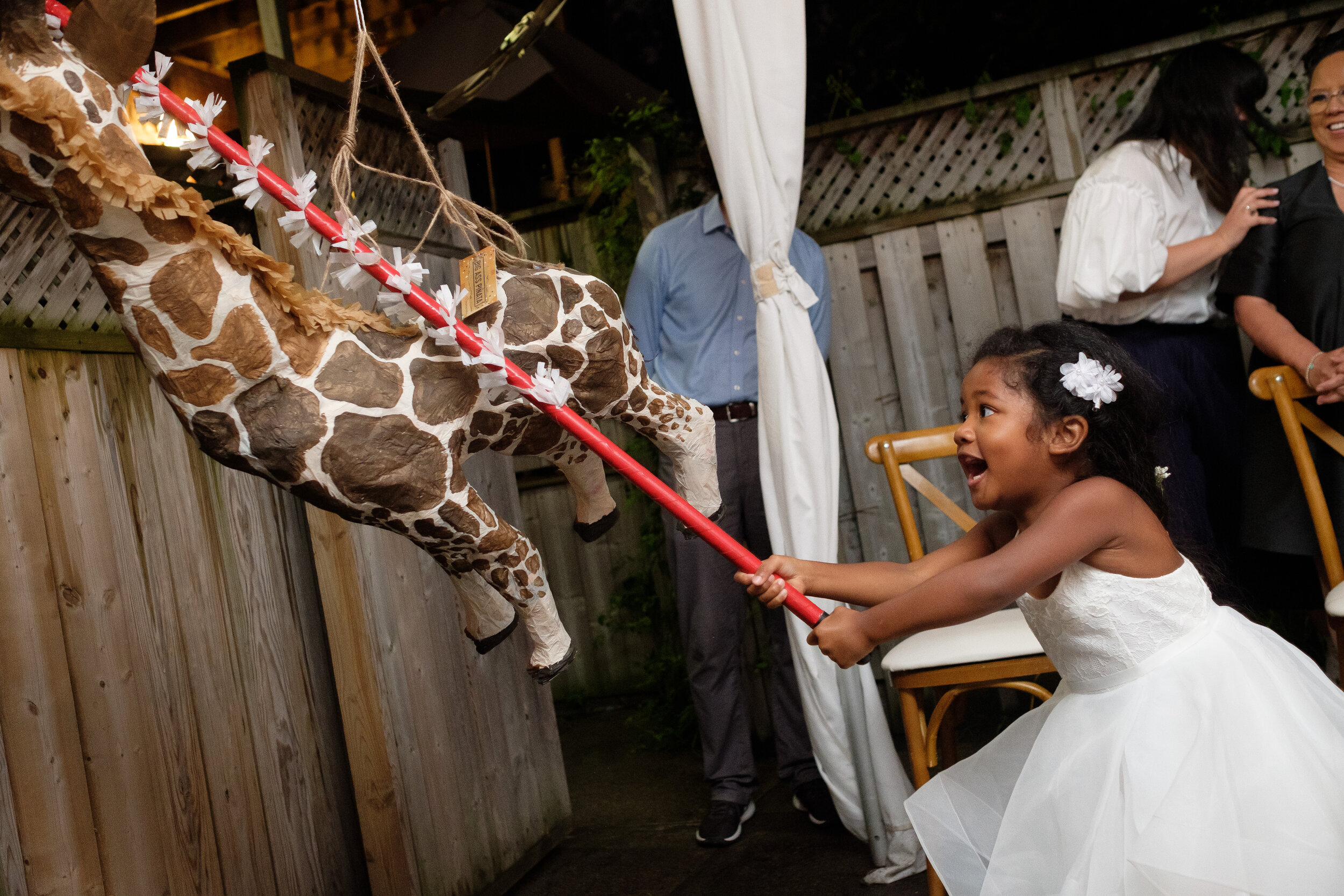  the flower girl hits a piñata during the reception at Geraldine &amp; Raphael’s backyard Toronto wedding by Toronto documentary wedding photographer Scott Williams (www.scottwilliamsphotographer.com) 