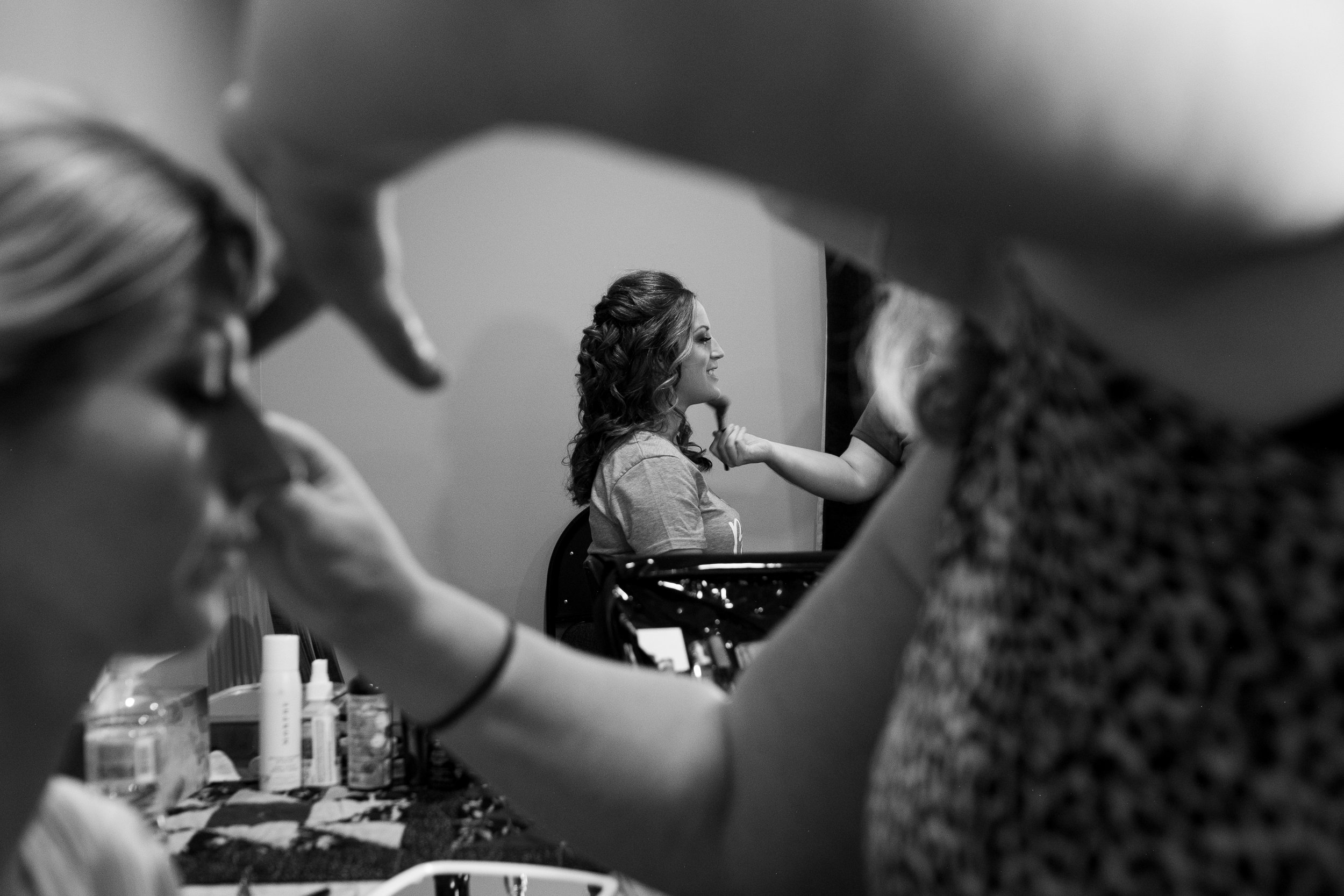  A candid black and white wedding photograph of a bridesmaid having her makeup done at the brides parents home before Cassandra and Antony’s wedding at the Hessenland Inn by Toronto wedding photographer Scott Williams. 