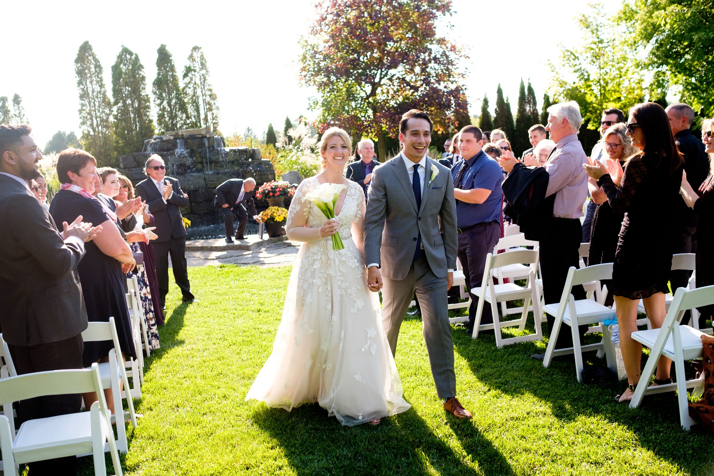  A candid colour wedding photograph after the outdoor wedding ceremony as the happy couple recedes down the aisle of  Cassandra and Antony’s wedding at the Hessenland Inn by Toronto wedding photographer Scott Williams. 
