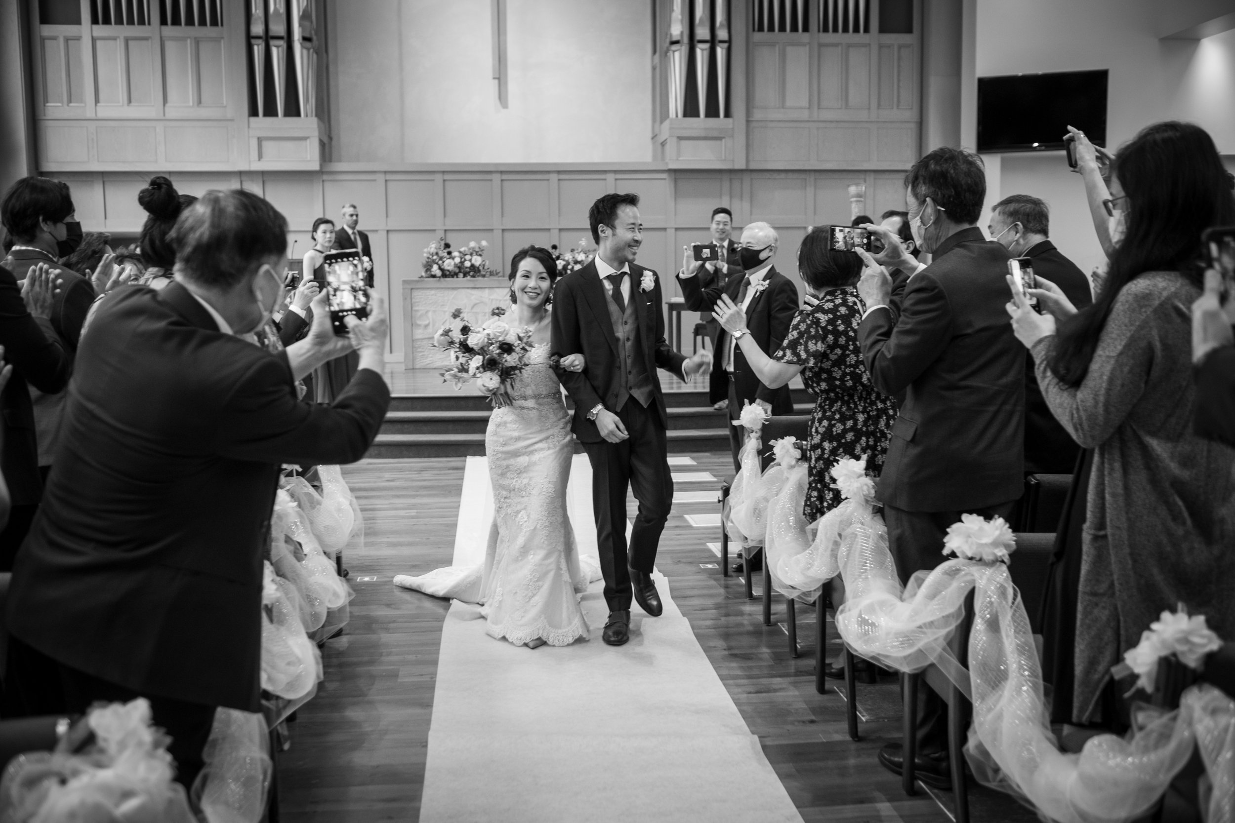  A candid wedding photograph of Jennifer + Jarvis walkingdown the wedding aisle at Lawrence Park Community Church  before their wedding reception later at Graydon Hall in Toronto, Ontario.  Photograph by Toronto Wedding Photographer Scott Williams.  