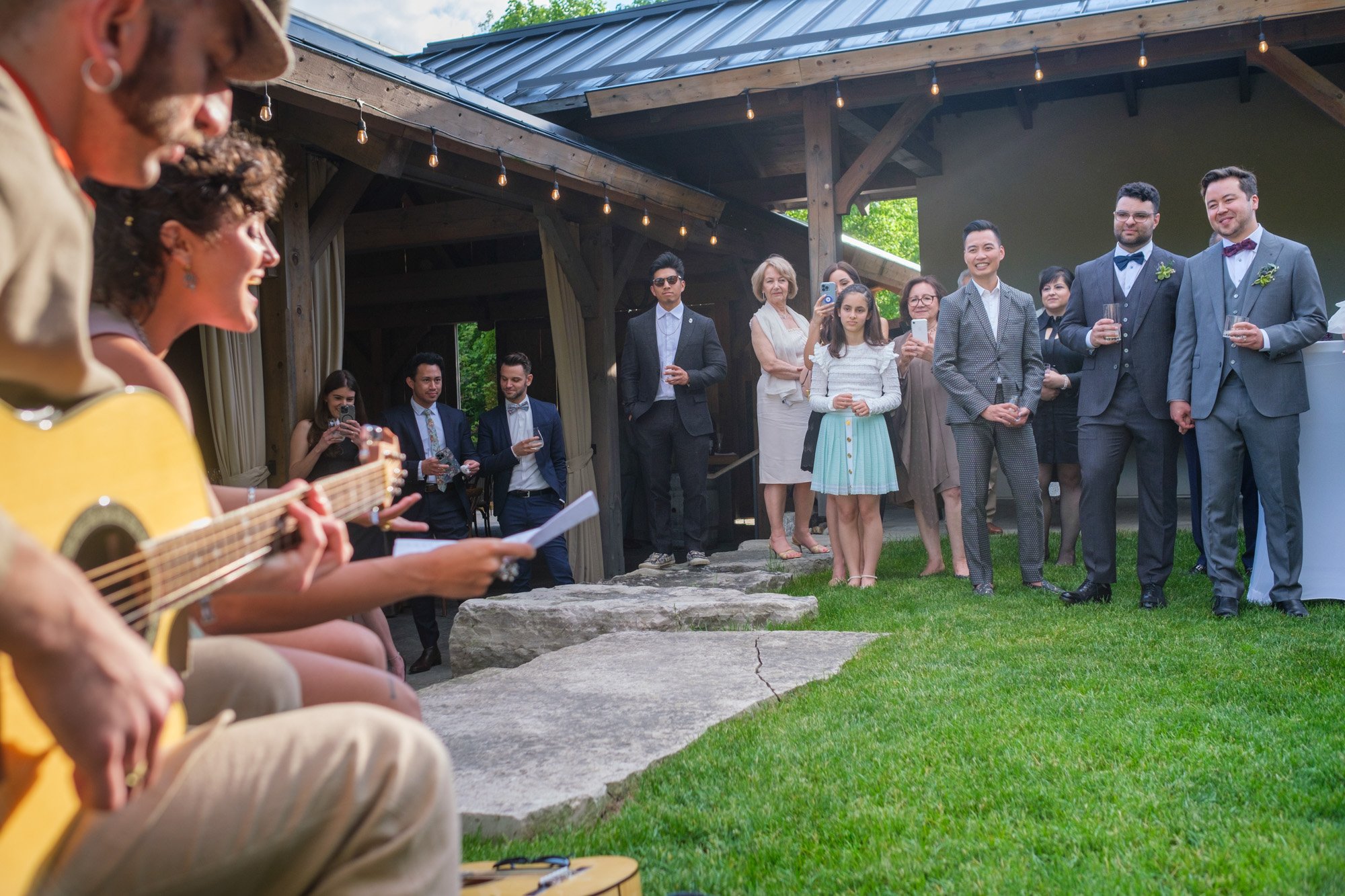  A colour candid wedding photograph of Greg and Damon’s cocktail hour at the Summer House as family members perform on the grounds of Langdon Hall   Photograph by Toronto wedding photographer Scott Williams (www.scottwilliamsphotographer.com) 