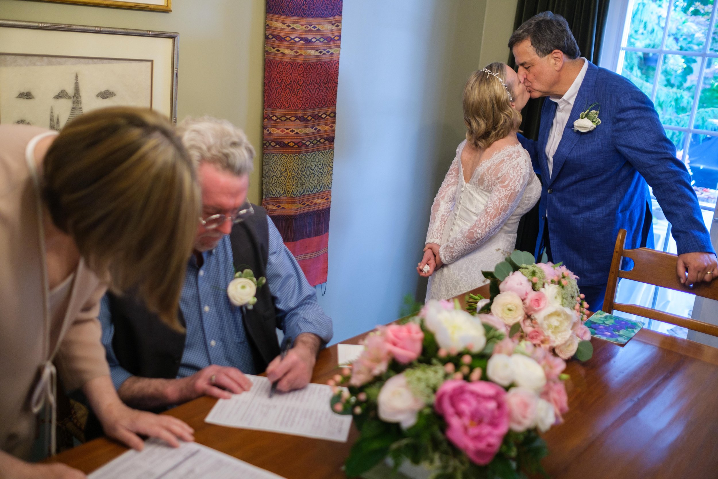  A colour candid wedding photograph from Katherine + Cameron’s wedding ceremony as their witness sign the marriage certificate during their intimate backyard wedding in Waterloo, Ontario by Toronto wedding photographer Scott Williams (www.scottwillia
