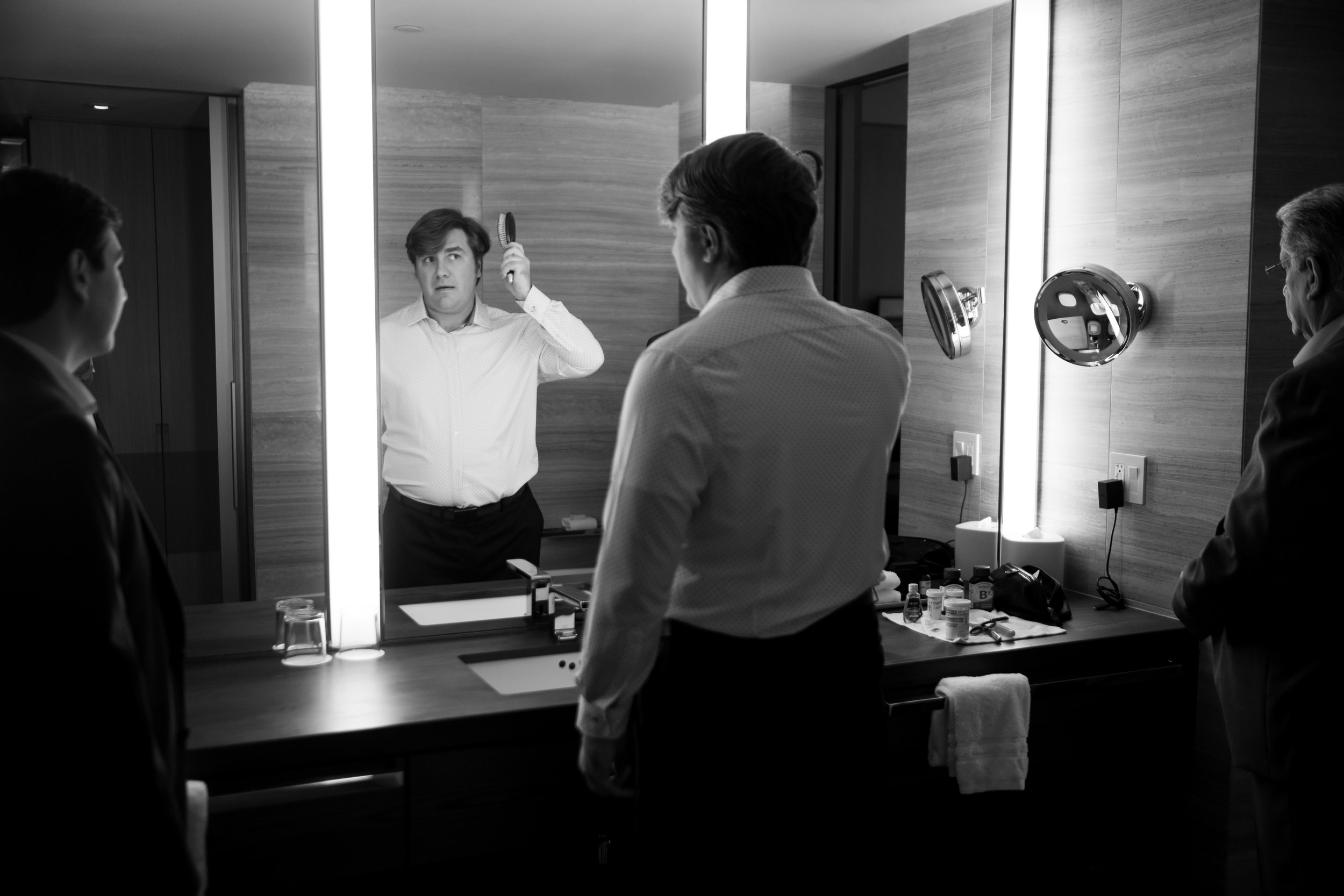  A black and white wedding photograph of Geoff getting ready  in a suite at the Four Seasons Hotel in the morning before his wedding at the Royal Canadian Yacht Club by Toronto wedding photographer Scott Williams  