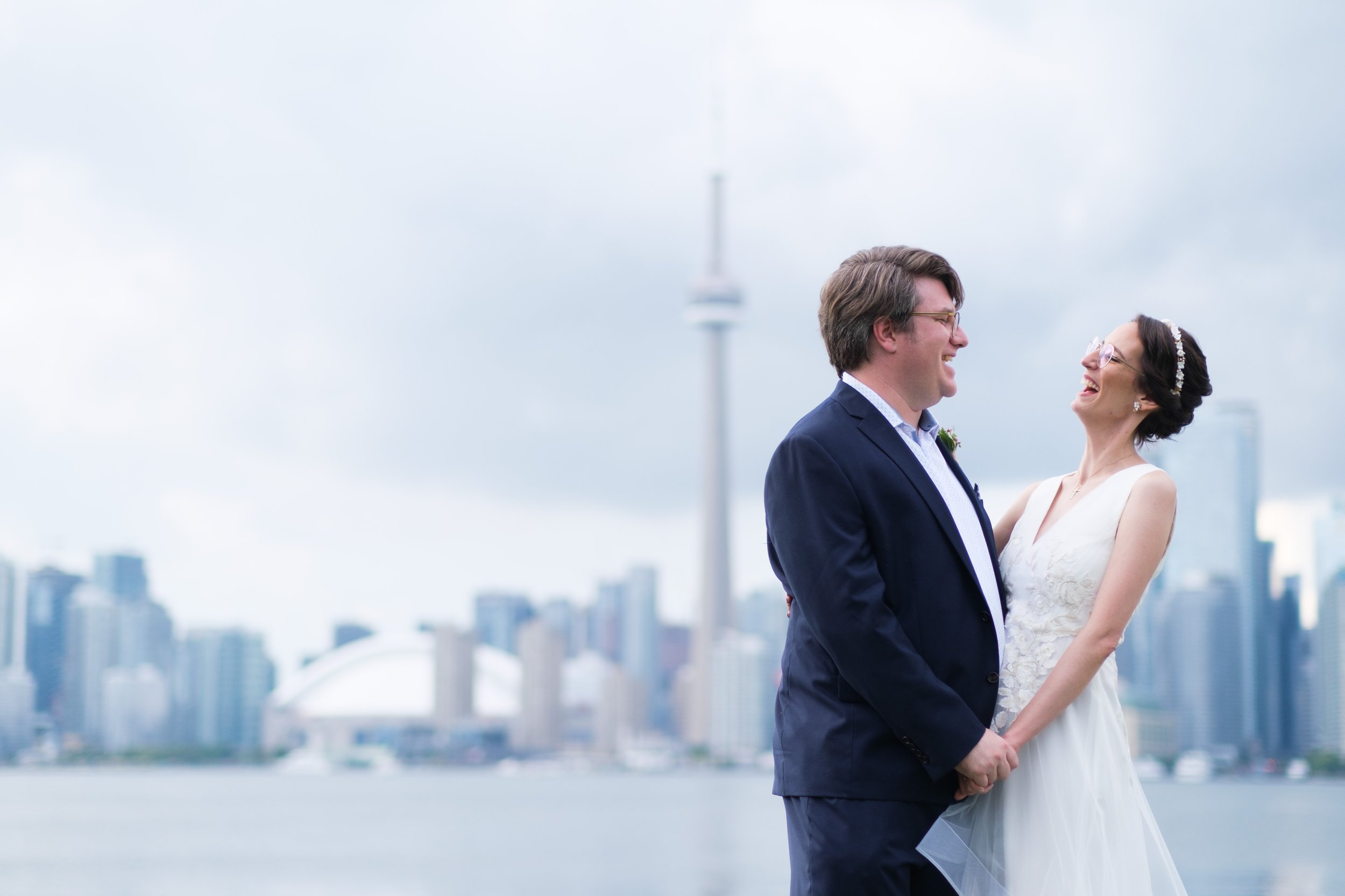  A colour wedding portrait  photograph of Rocio’s and Geoff with the Toronto city skyline in the background taken on the grounds of the Royal Canadian Yacht Club by Toronto wedding photographer Scott Williams  