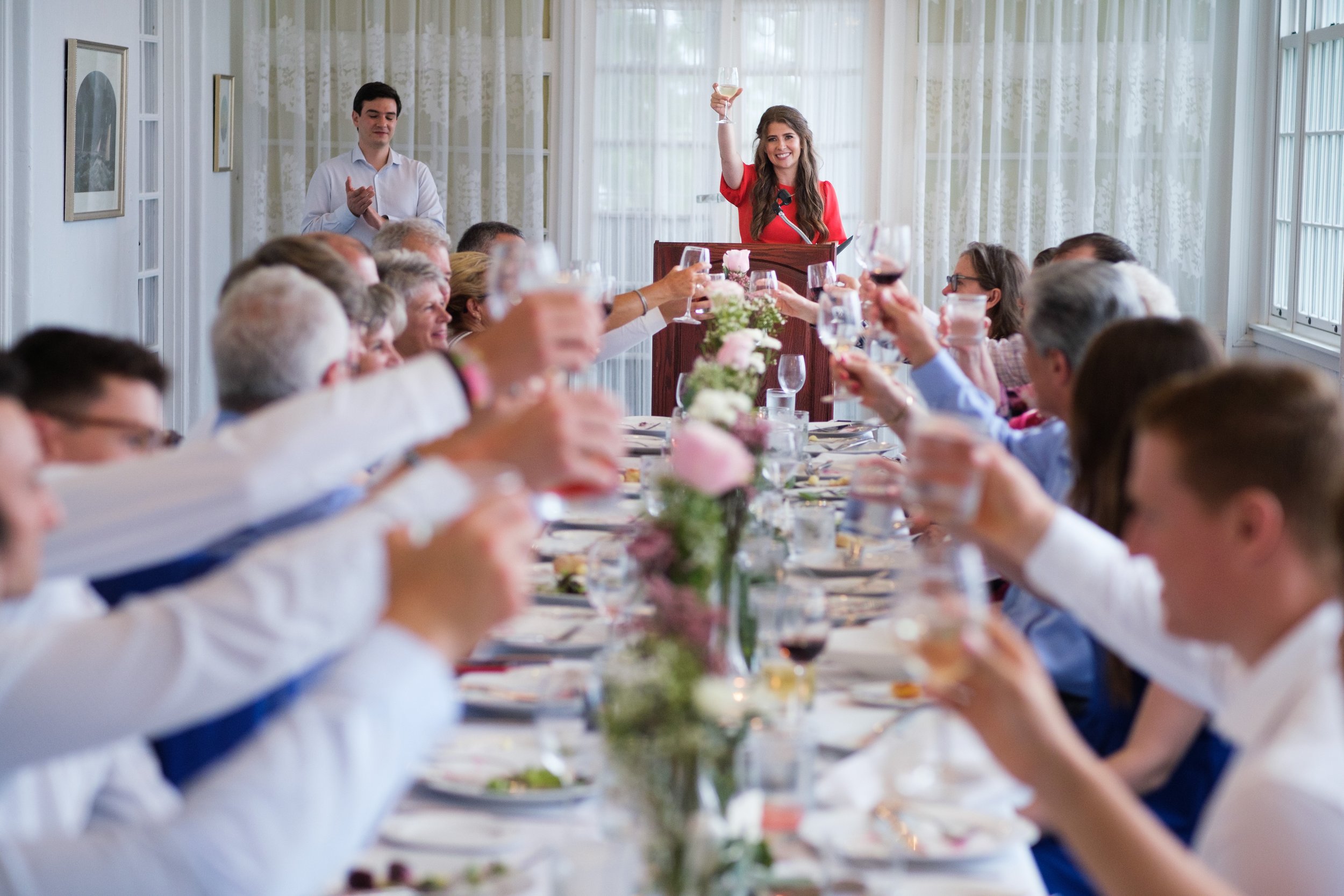  A colour wedding candid photograph of Geoff’s sister giving a wedding toast during the intimate dinner reception at the Royal Canadian Yacht Club by Toronto wedding photographer Scott Williams  