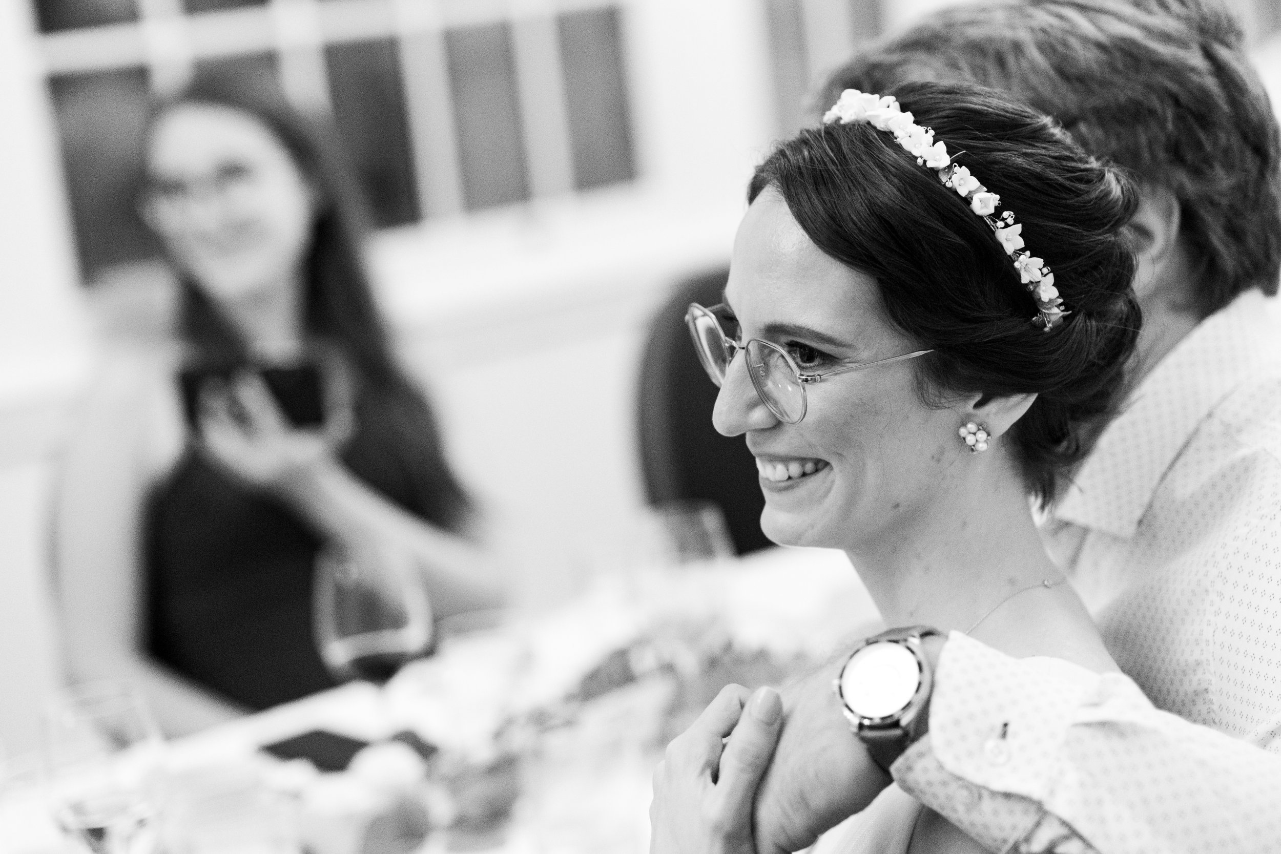  A black and white wedding candid  photograph of Rocio watching a toast at her wedding reception at the Royal Canadian Yacht Club by Toronto wedding photographer Scott Williams  