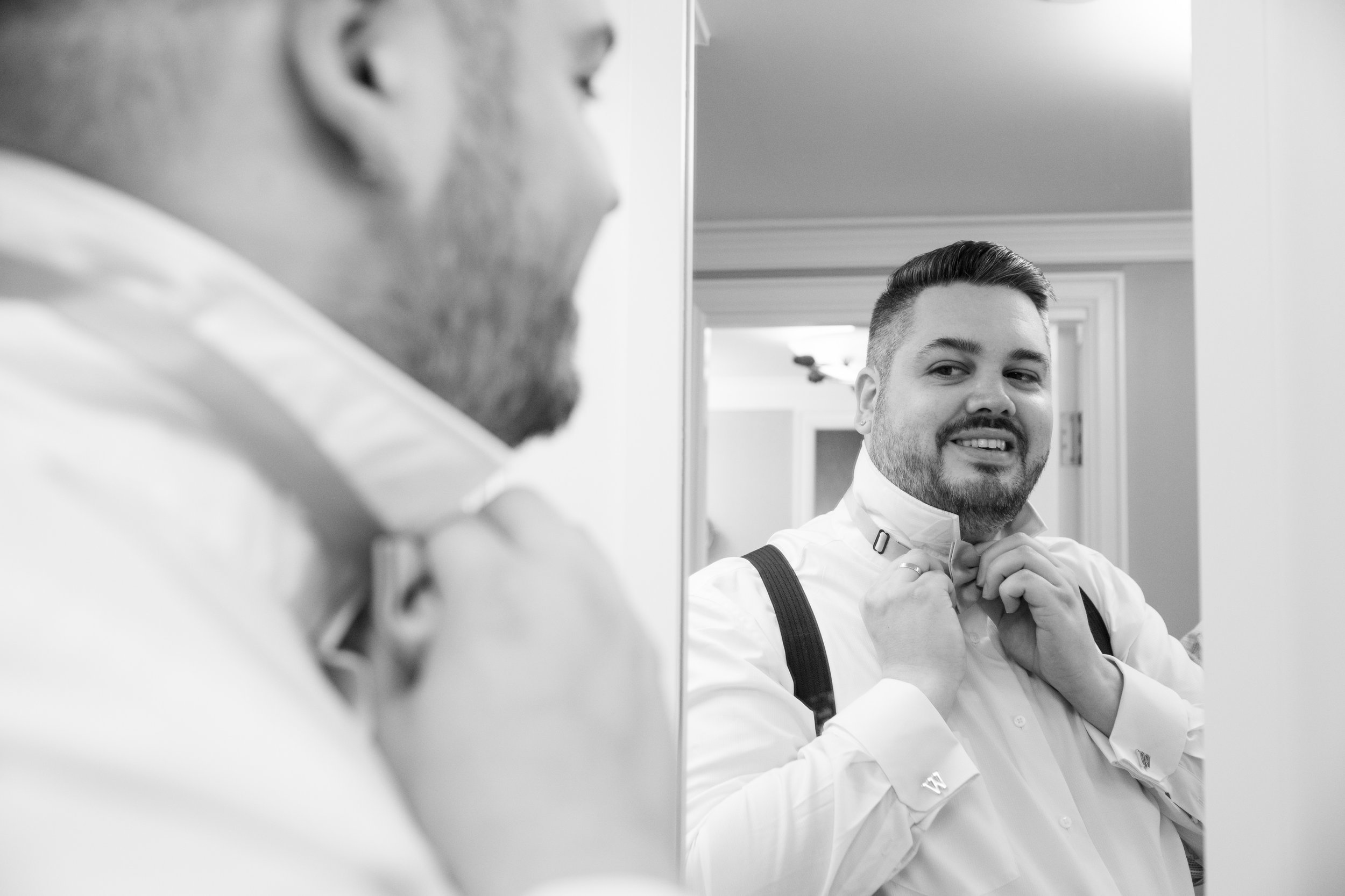  A black and white candid wedding photograph of the groom getting ready in his hotel suite before Bryan + Adam’s wedding  at the JW Marriot The Rosseau in Muskoka by Toronto wedding photographer Scott Williams (www.scottwilliamsphotographer.com) 