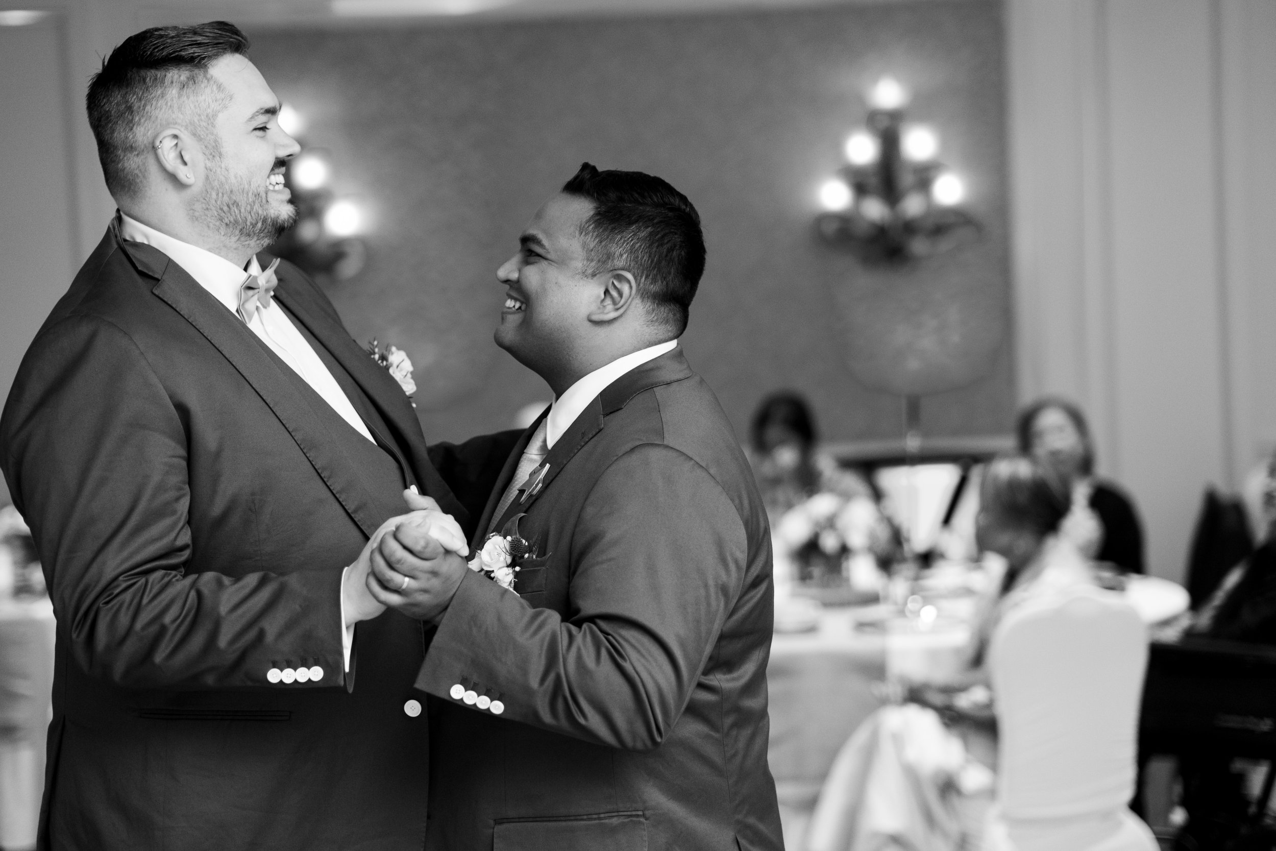  A black and white candid wedding photograph of Bryan + Adam enjoying their first dance as a married couple during the wedding reception at the JW Marriot The Rosseau in Muskoka by Toronto wedding photographer Scott Williams  