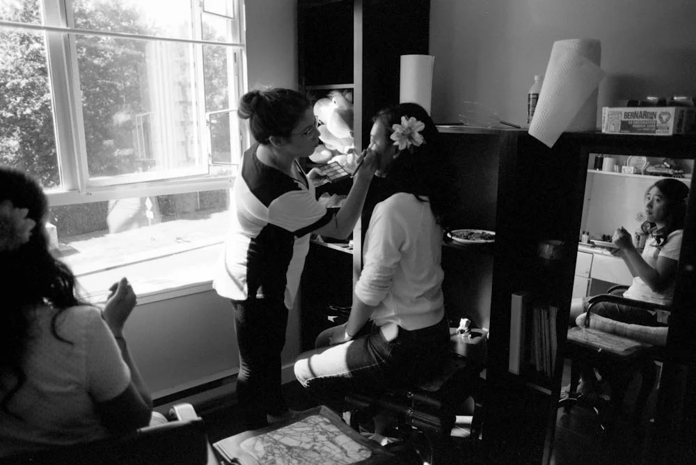 One of the bridesmaids looks on as Monica has her makeup done.