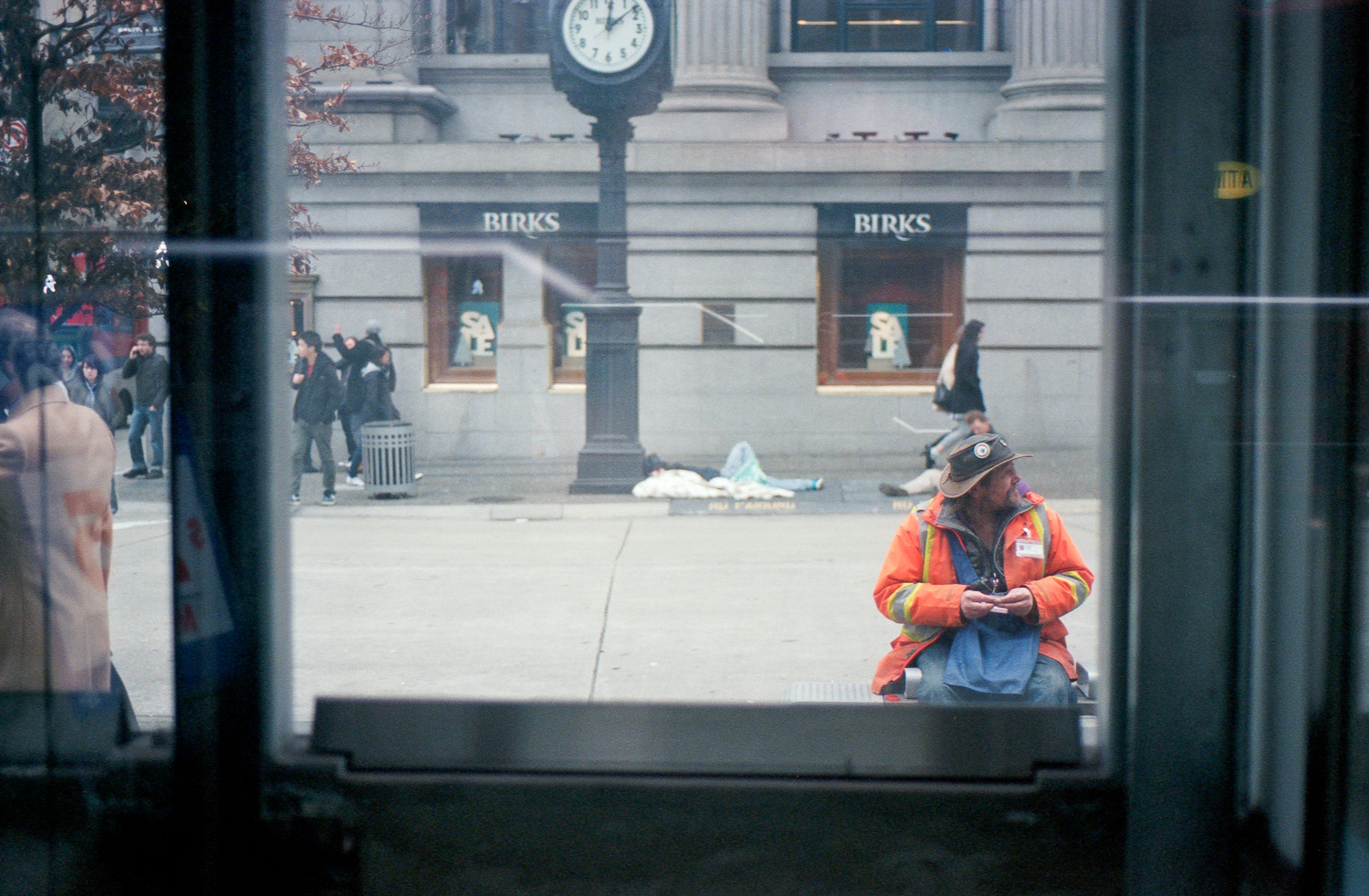 The gentleman in the orange sells the Megaphone magazine. Check out what they do at: http://www.megaphonemagazine.com/