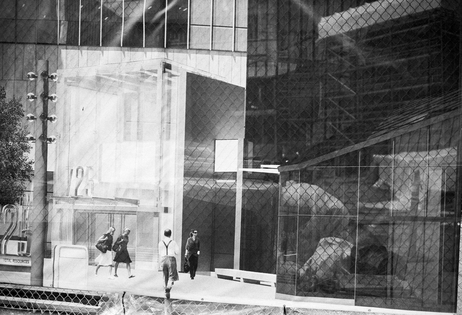 It may be a bit confusing at first but the people in the image are actually part of an image that is placed on a fence that surrounds a work site.