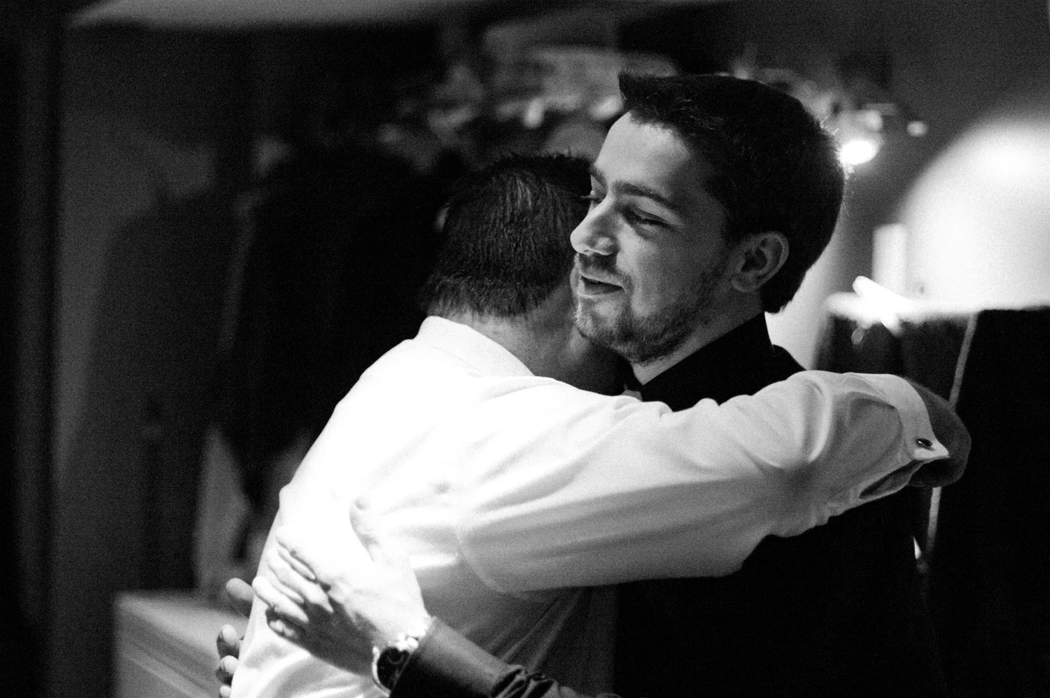 We wedding photographers work in very difficult light situations. In this specific situation with the groom (on the right) and his groomsmen hugging him, this was a basement with very little lights other than a few ceiling spot lights and a door. I could have used flash to brighten things up but decided that staying true to the lighting of the scene would (a) not draw attention to myself (if I fired my flash, people would instantly know I was there) and (b) allow a truer representation of what it felt like to be there.