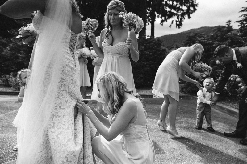 This image happened in the spur of the moment. I was just hanging out with the bride in the back of the ceremony area when I saw this all come together. At first I spotted the bridesmaid helping the bride in the dress but then saw the element on the right all come together. (Seconding for Jody Nay Photography)