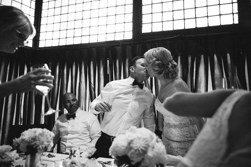 I enjoy having a foreground element and a background element to help provide focus on my focal point. Here, I saw the bride and groom going in for a kiss but saw also the bridesmaids (after having made their speech) making their way back to the table. I saw all the elements coming together and knew I only had one chance to get the shot I wanted... so I waited for the bridesmaids to cross my path and took this as the bride and groom kissed, with one of the groomsmen looking on.
