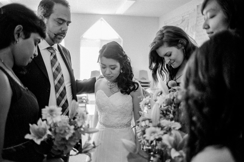 The bride prays with the bridesmaids and her pastor before heading down to the ceremony.