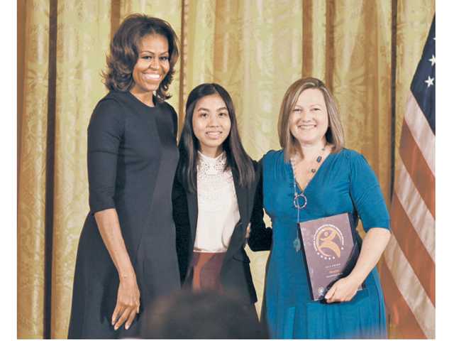 First Lady Michelle Obama, left, presents the 2013 National Arts and Humanities Youth Program award to Jacqueline Uy, center, a 16-year-old aspiring journalist and WriteGirl participant, and WriteGirl Executive Director Keren Taylor.