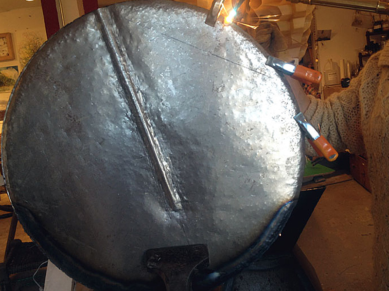 Welding the seam of 22 gauge steel to make a shape resembling a ceramic capacitor. This will serve as an armature. Finishing work will be done with Bondo and sanding to hide imperfections, such as the dimples caused by the pining hammer.