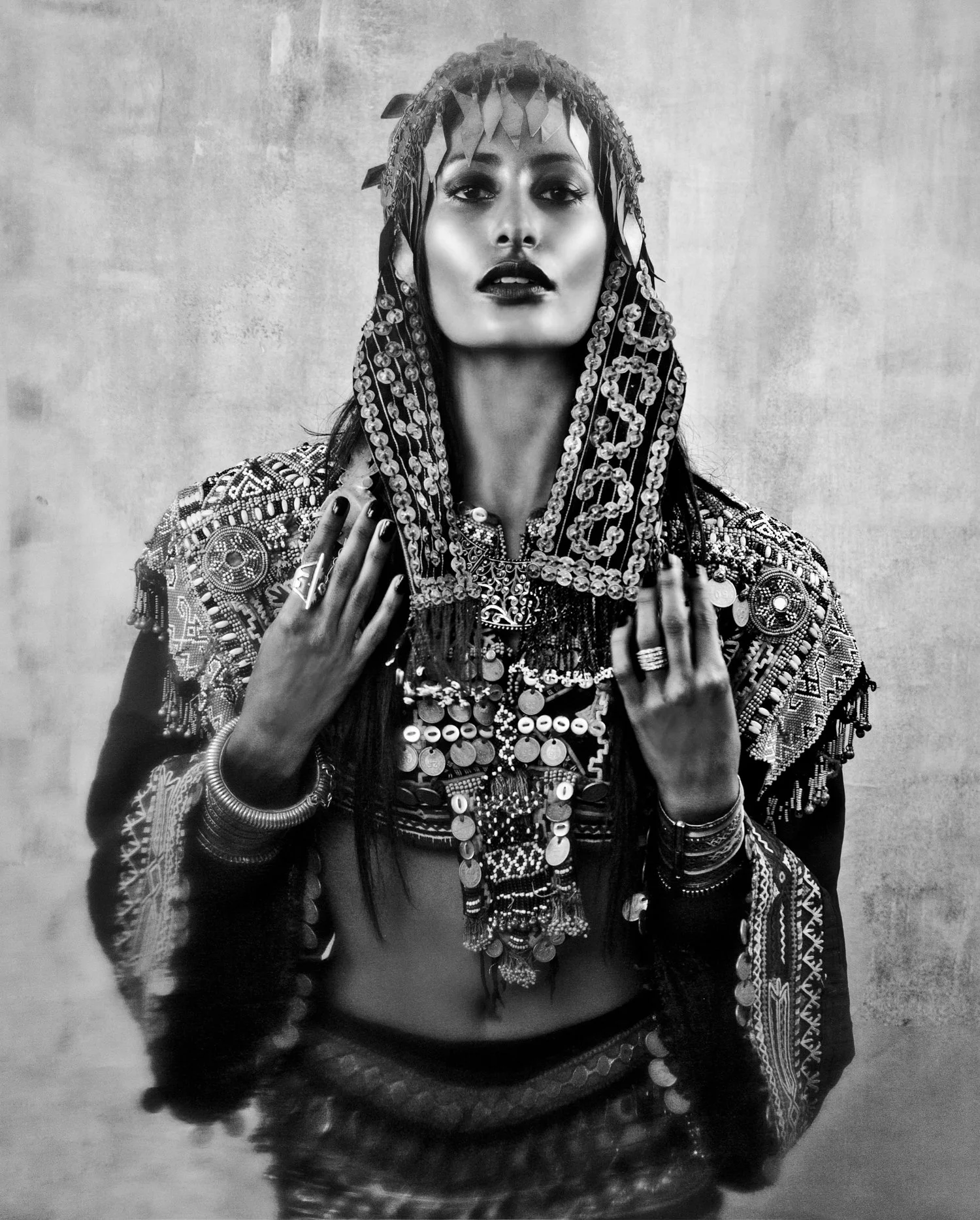 Black and white photograph of a woman wearing traditional, ornate jewelry and clothing, with a serious expression.