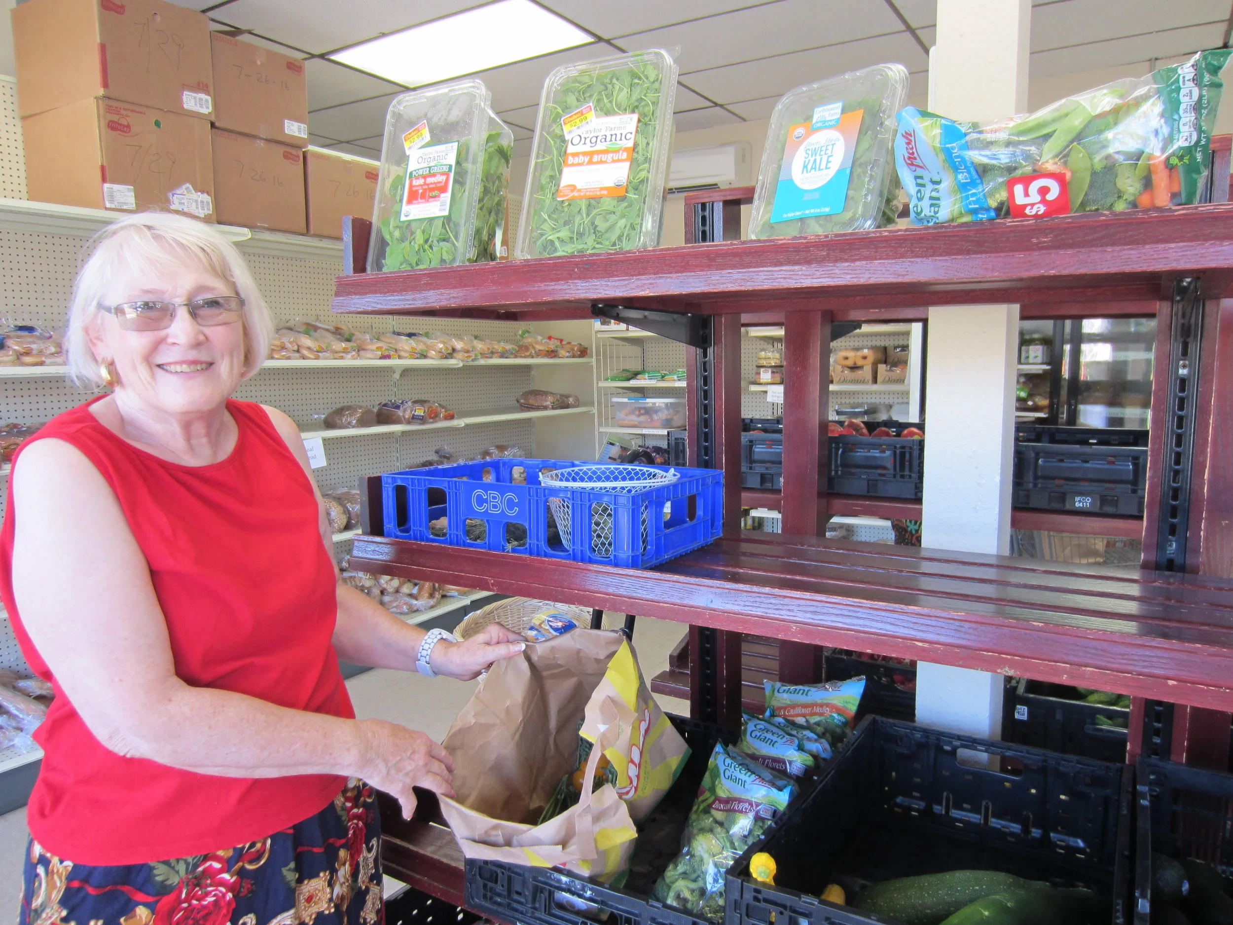 Lynda, a St Johns Food Share member and volunteer, shows off available options at the store. 