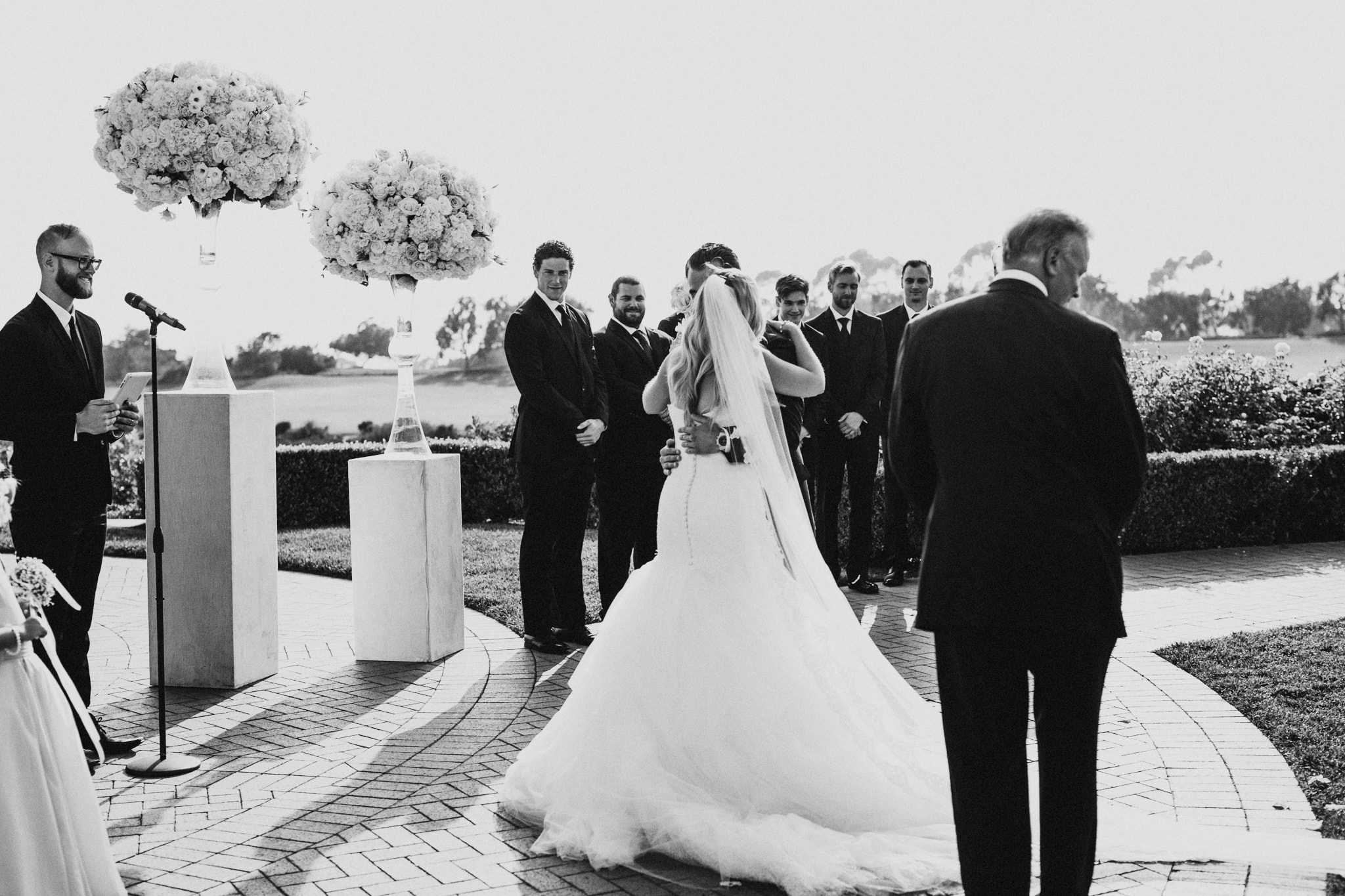 A groom hugs his bride at an outdoor wedding ceremony in Orange County, California.