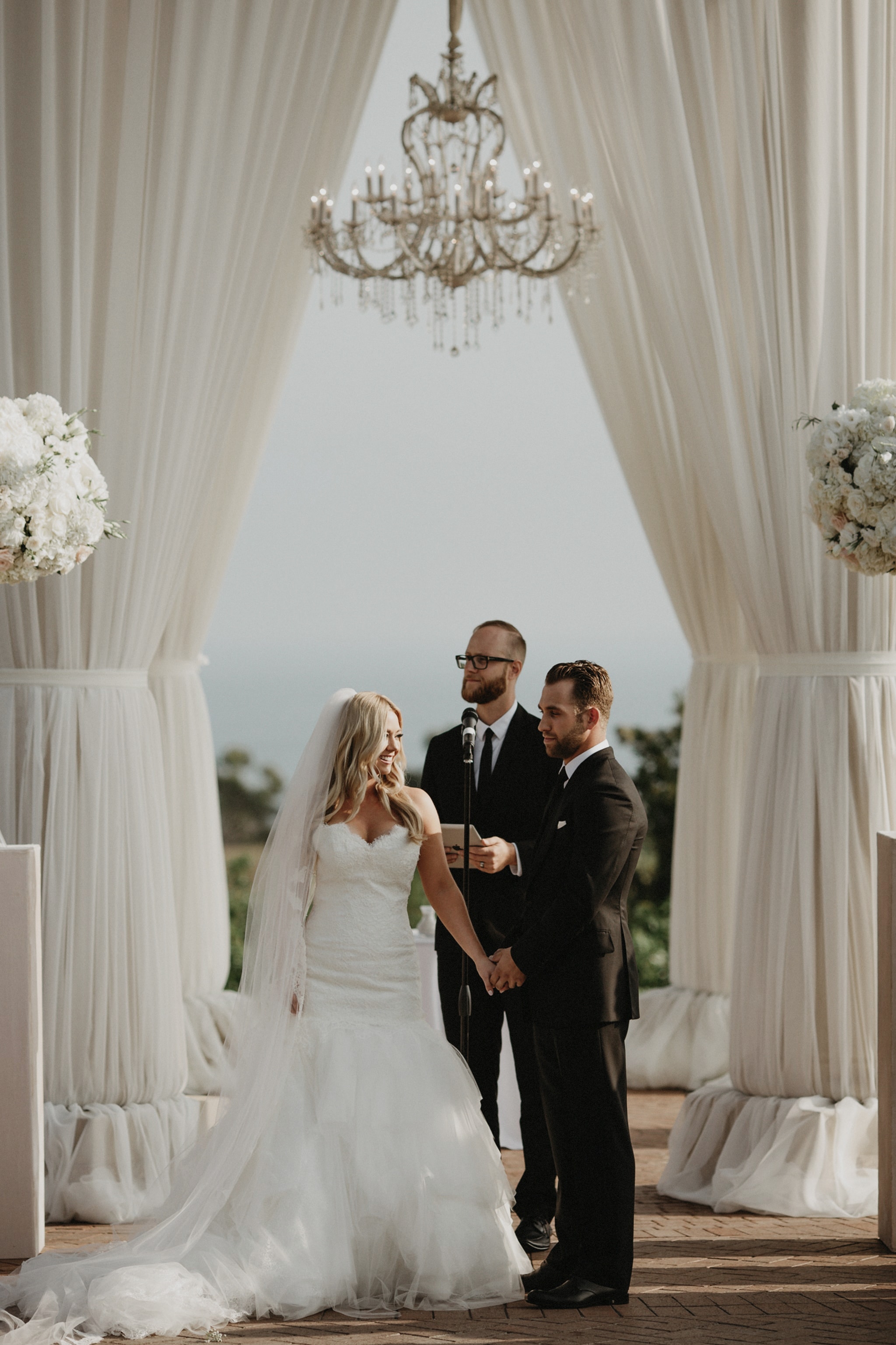 A bride and groom hold hands at the alter during a wedding ceremony at Pelican Hill Resort in Californa.