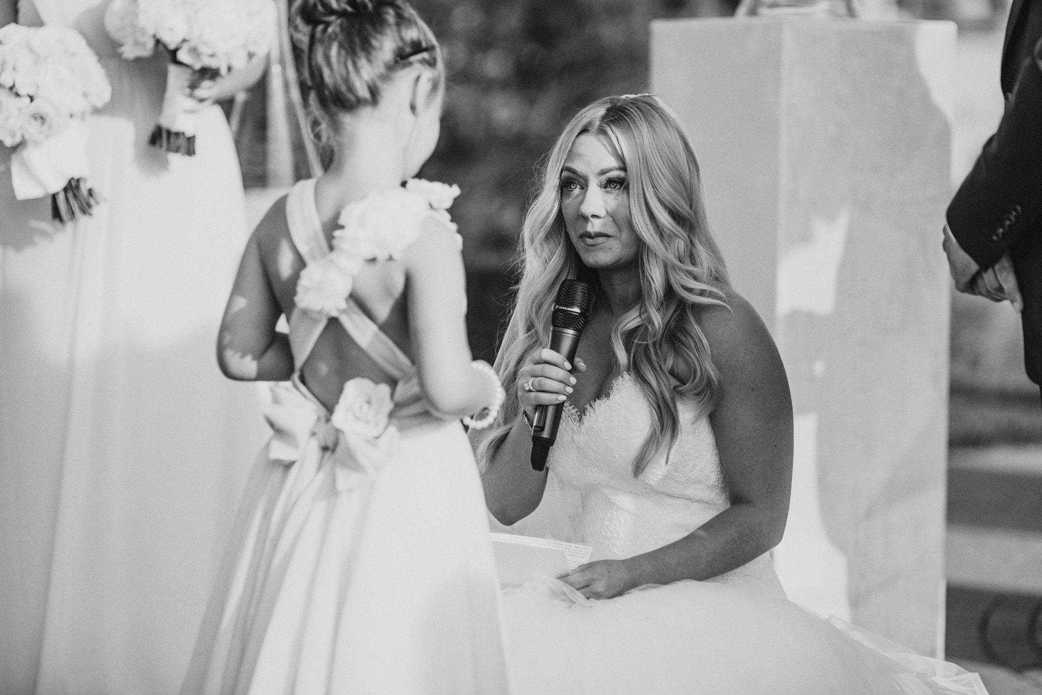 A bride speaks to a flower girl during her beautiful outdoor wedding ceremony in Orange County, California.