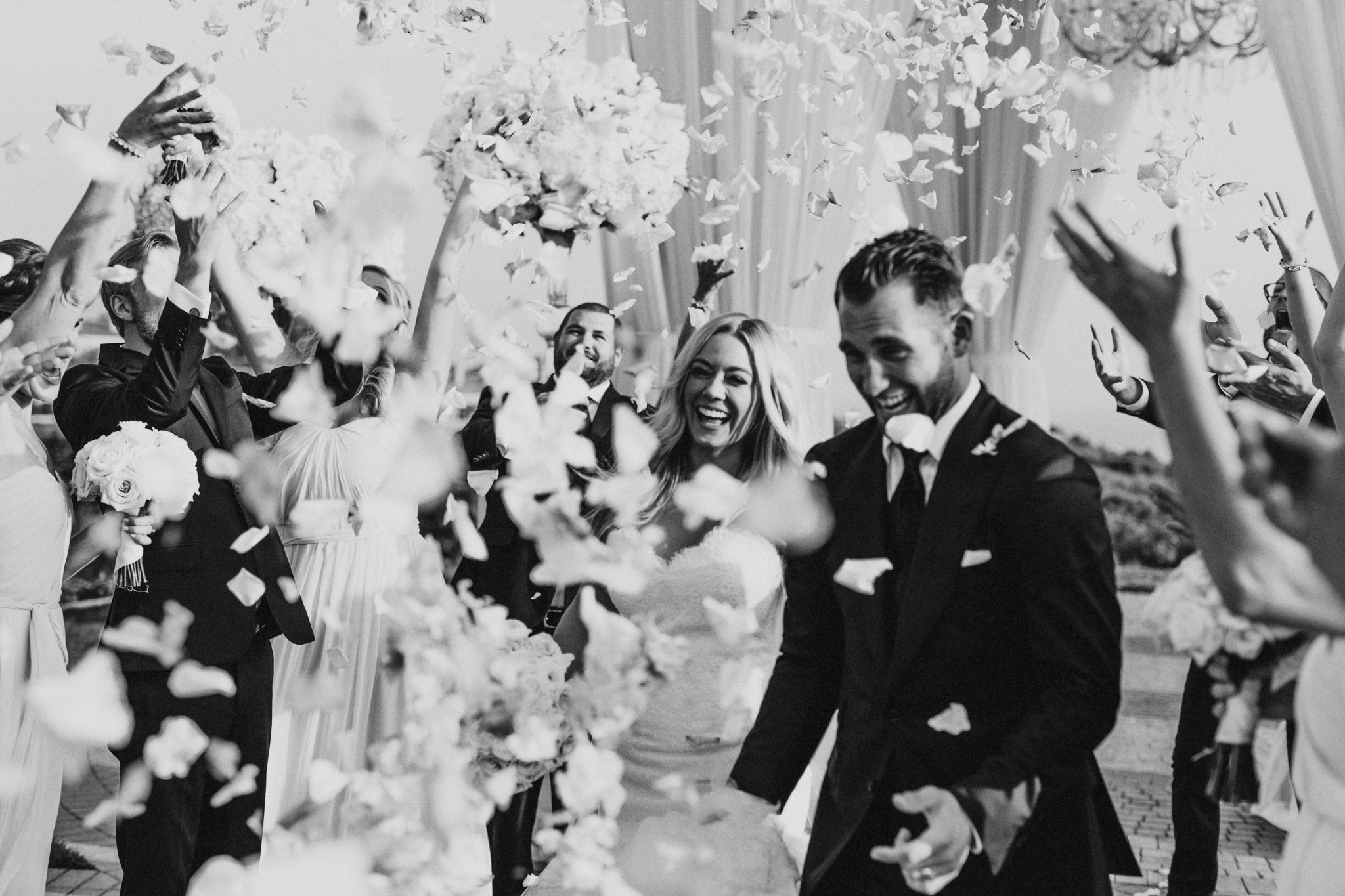 Guests throw petals as a happy bride and groom walk up the aisle during their Newport Beach wedding.