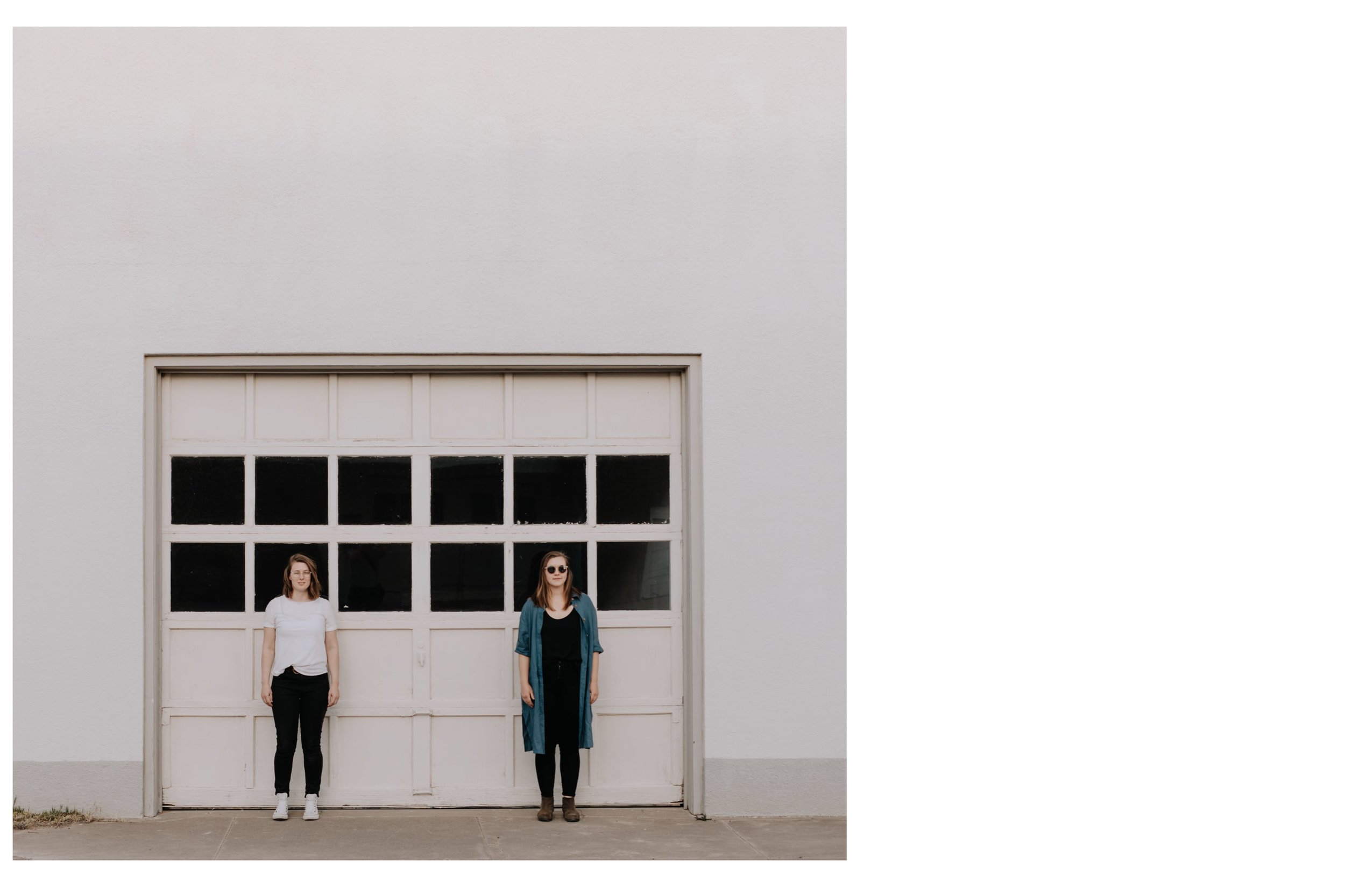 Two women stand in front of a white garage door during an edgy photoshoot in Marfa, Texas, with Josh Olson Photography.