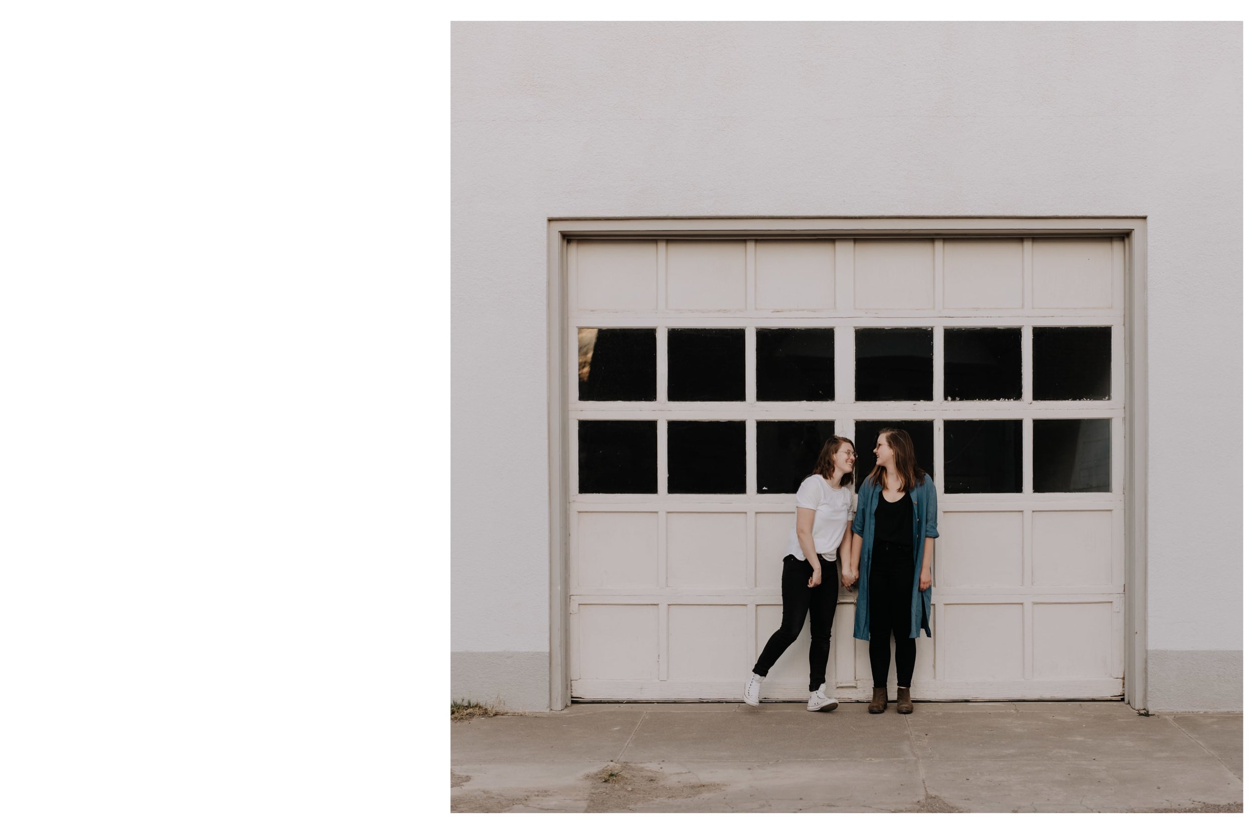Two women hold hands and pose in front of a white garage door during a photoshoot with Marfa photographer Josh Olson.