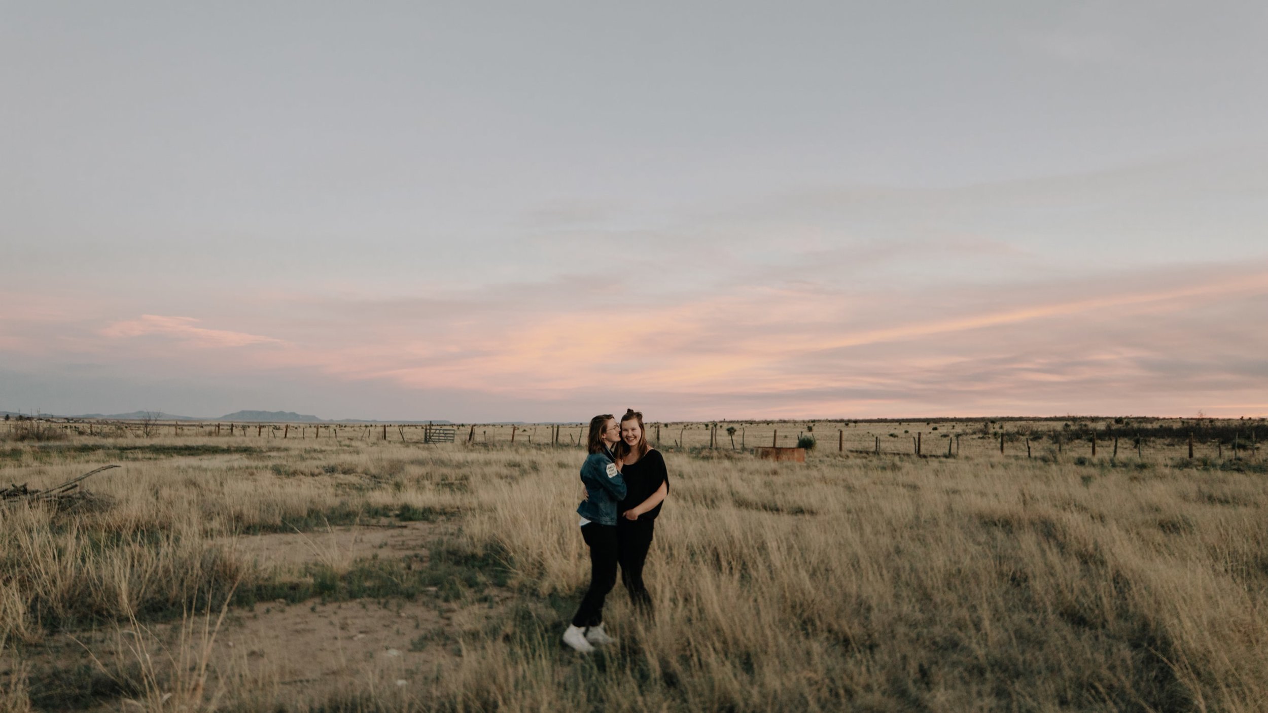 Two women embrace in a field during sunset in Marfa, Texas.