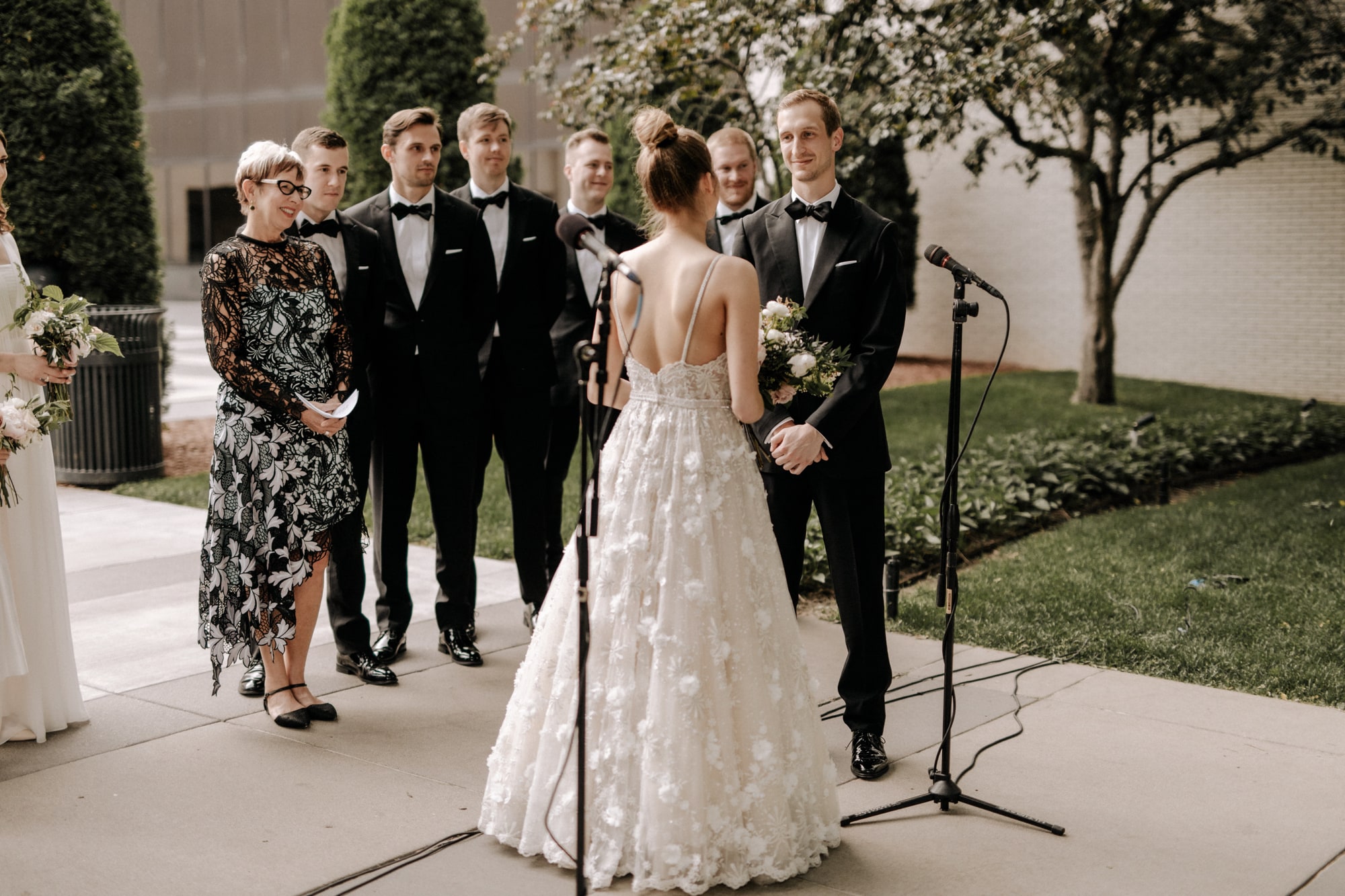 A bride and groom exchange vows while their wedding party watches happily during a wedding ceremony at the Minneapolis Institute of Art.