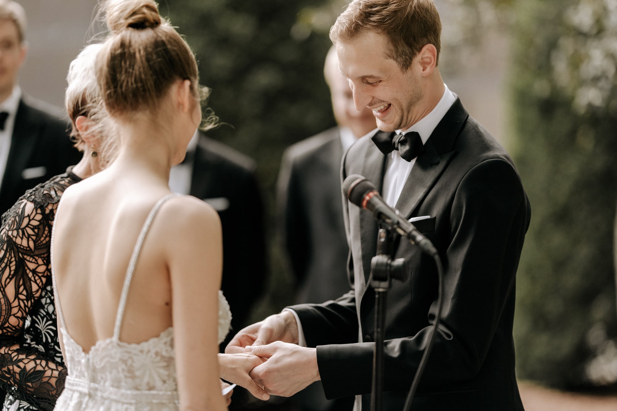 A groom smiles enthusiastically while placing a ring on the finger of his new bride during a beautiful wedding at the Minneapolis Institute of Art.