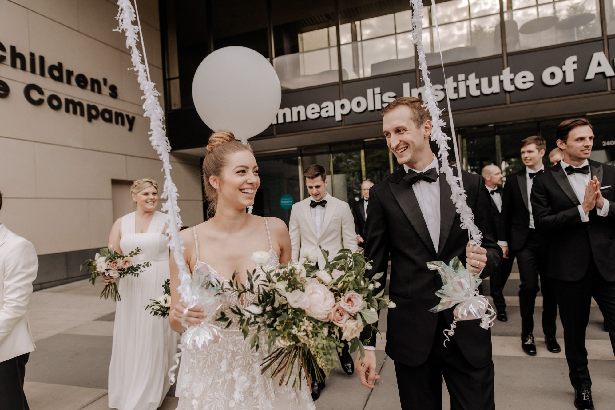 A happy bride and groom smile while walking outside of the Minneapolis Institute of Art.