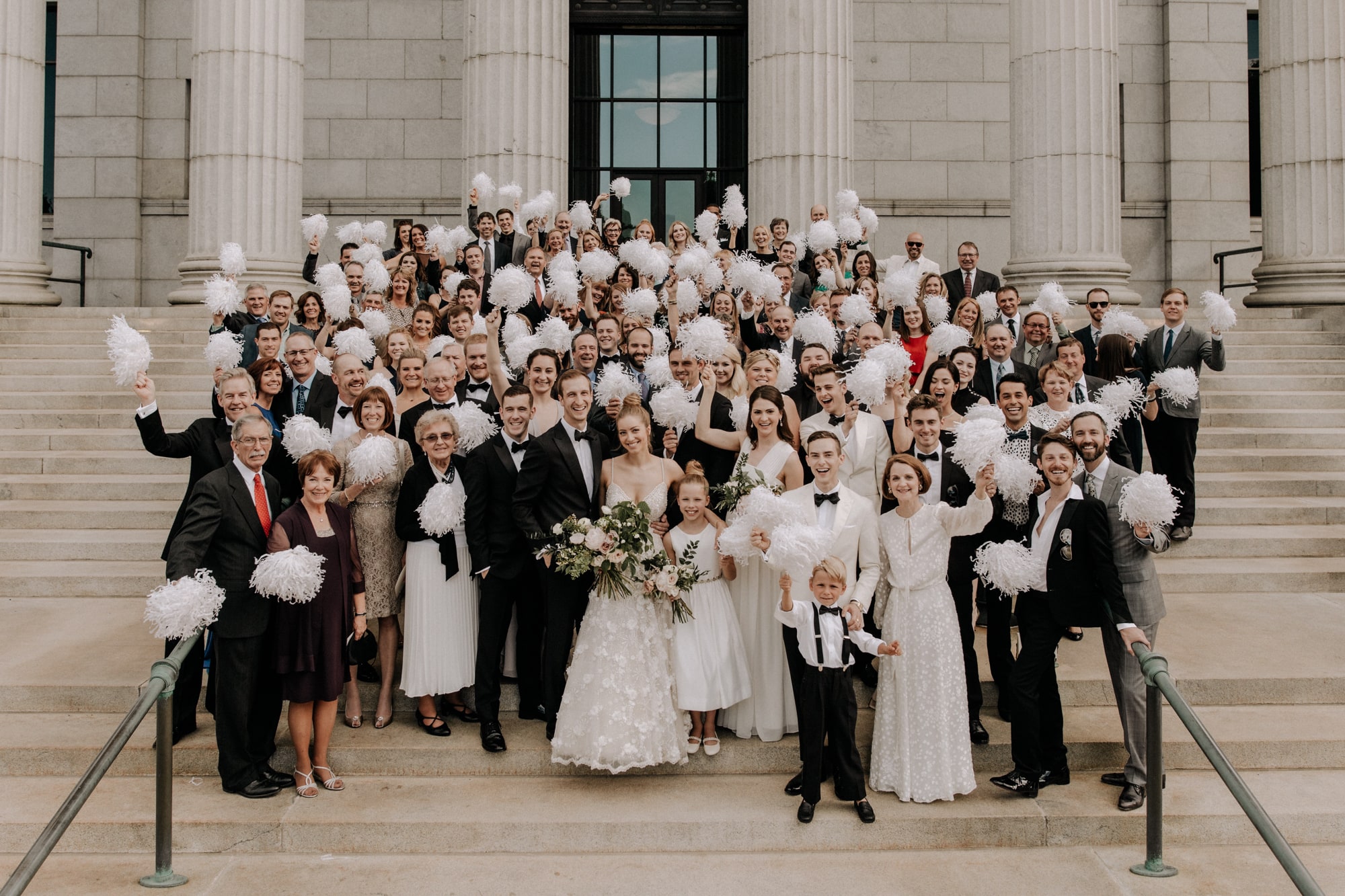 A large group of family and friends gather on the stairs of the Minneapolis Institute of Art for wedding photos with J.Olson Weddings.