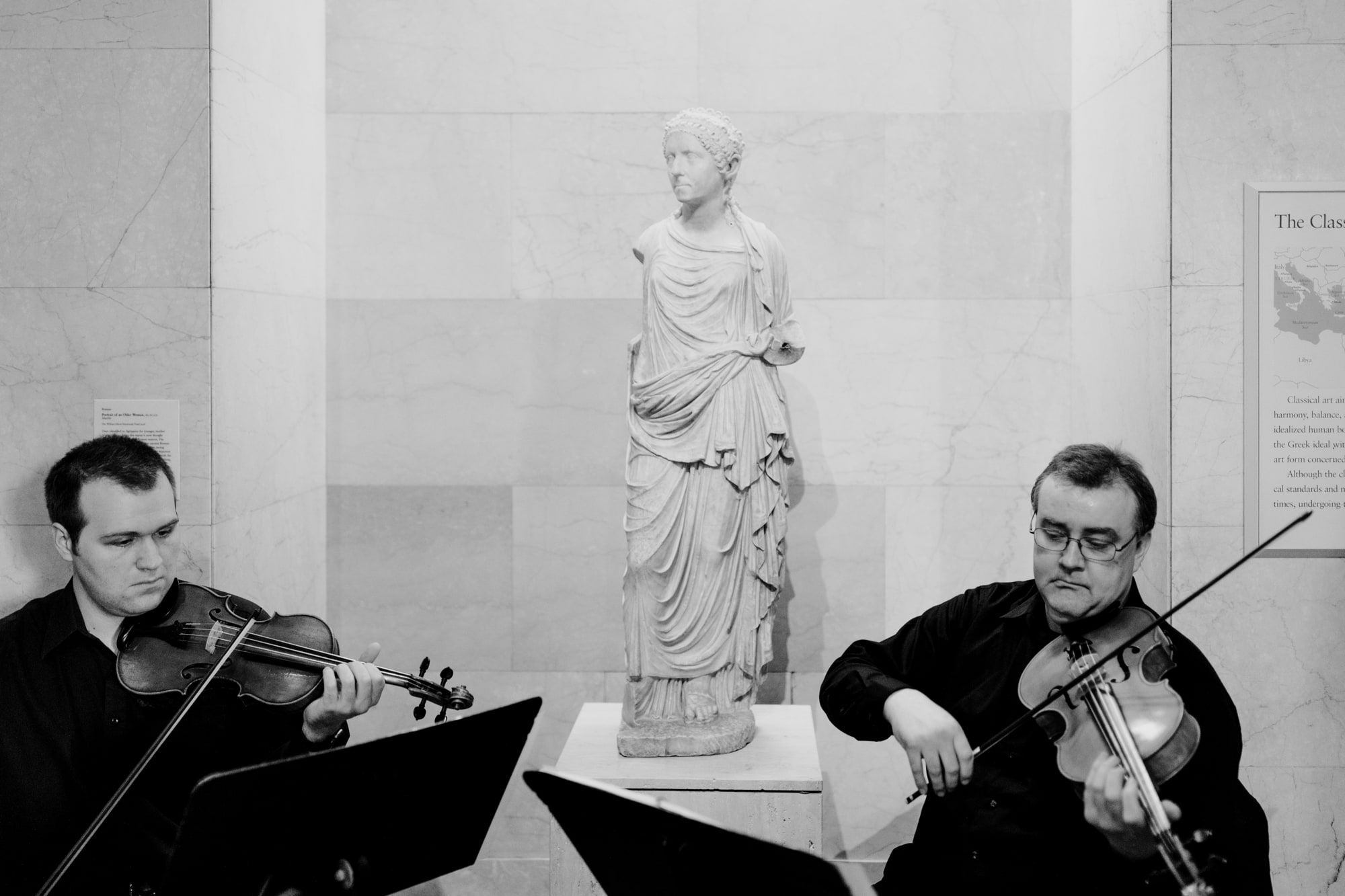 Musicians play the violin in front of a statue during a beautiful wedding at the Minneapolis Institute of Art.