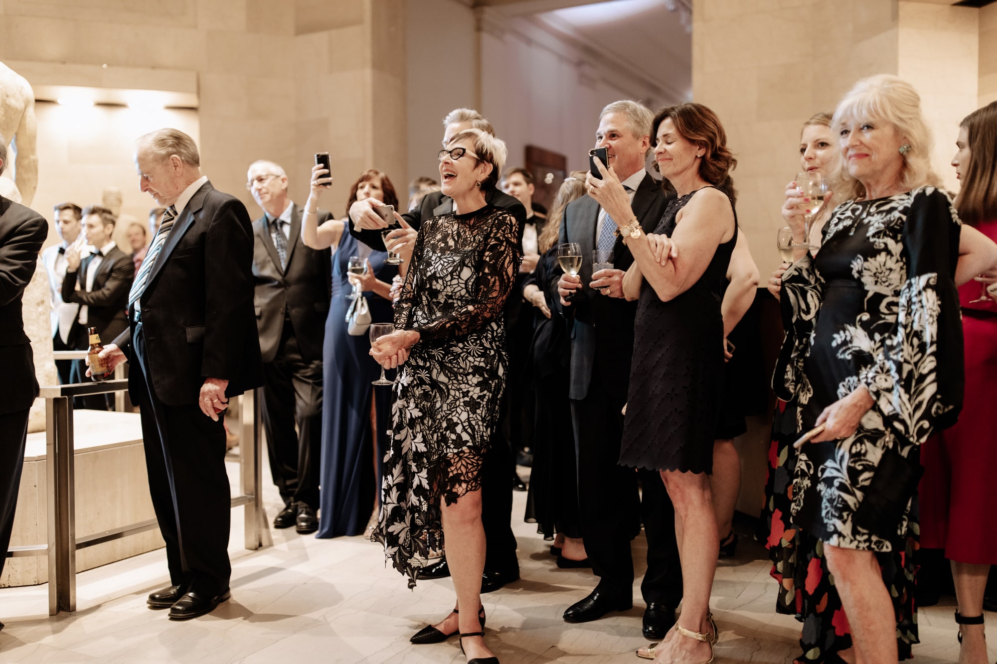 Guests smile and take pictures on their cellphones during wedding speeches inside the Minneapolis Institute of Art.