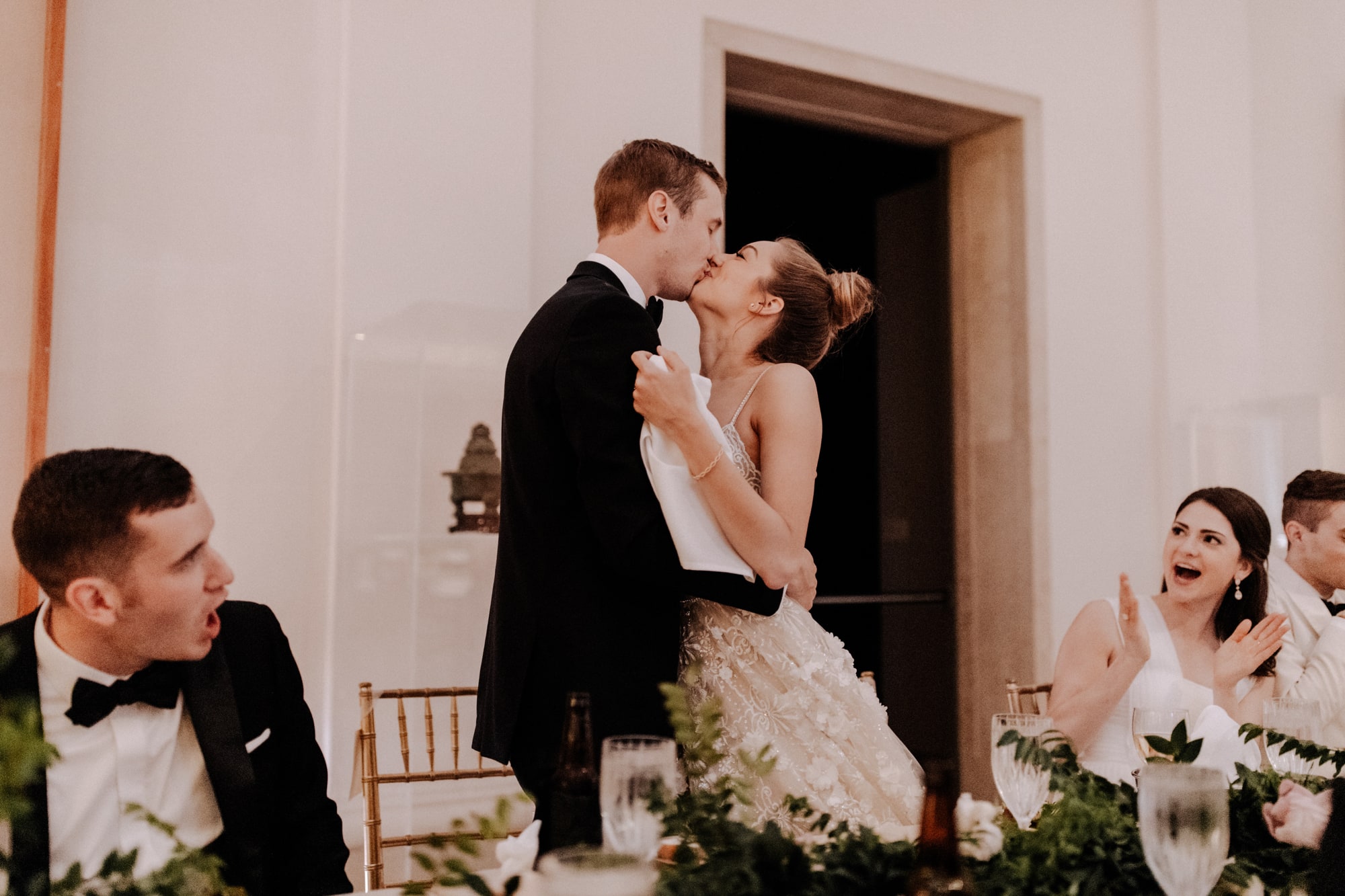 A bride and groom stand to kiss during their wedding dinner inside the Minneapolis Institute of Art.