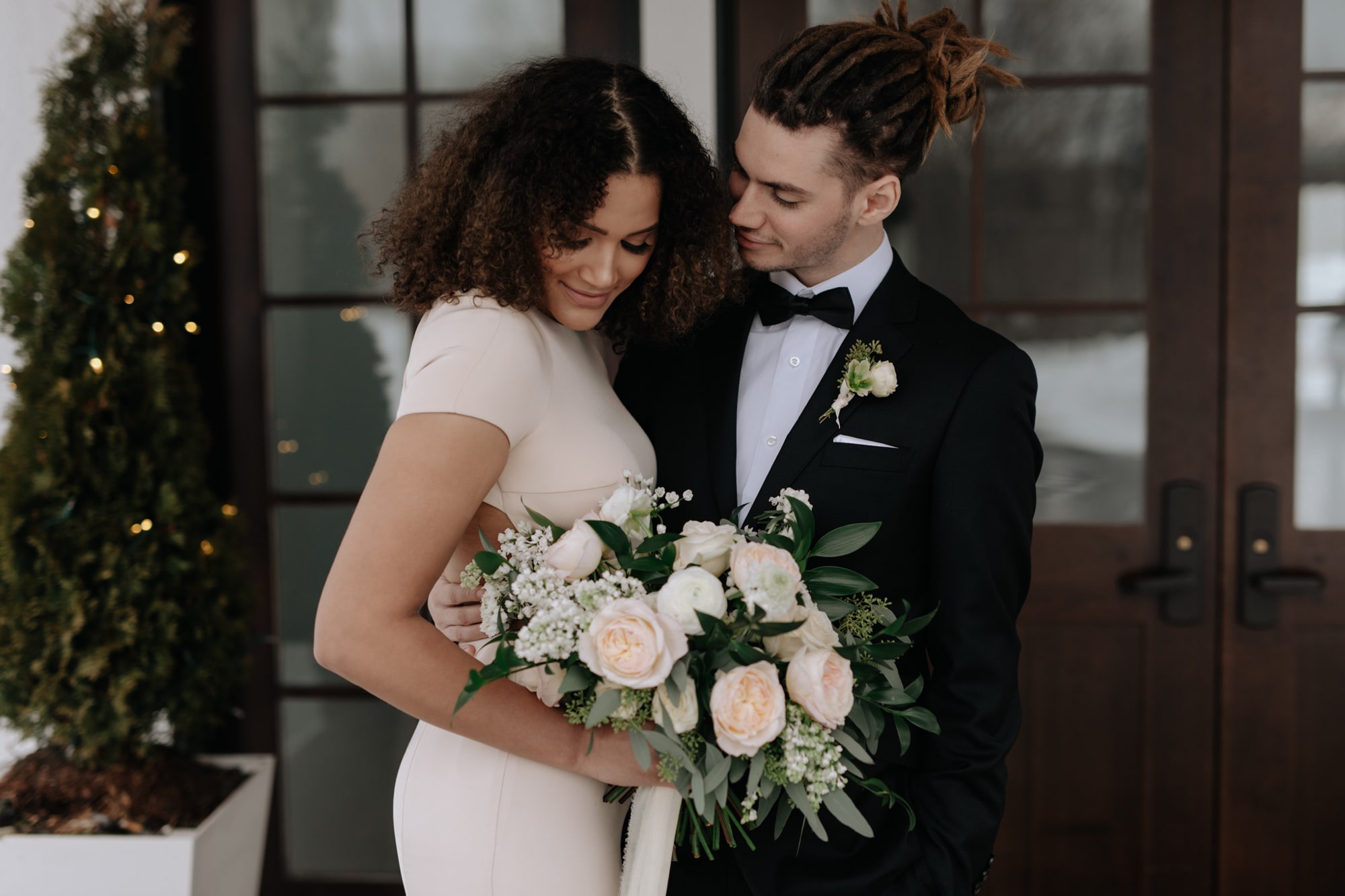 A beautiful bride smiles, embraced by her groom while holding a large bouquet in Minneapolis.