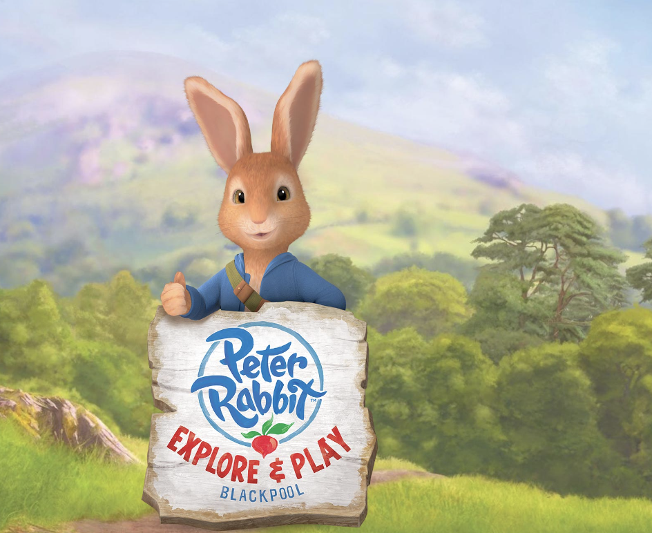 Coelho de desenhos animados segurando uma placa com o logo do Peter Rabbit e o texto "Explore & Play" em um cenário verde com colinas e árvores.
