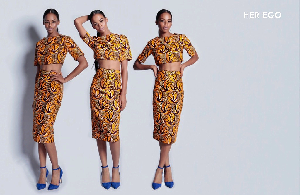 Woman wearing a yellow African print dress. The image is edited to show her standing next to an identical image of herself 3 times. 