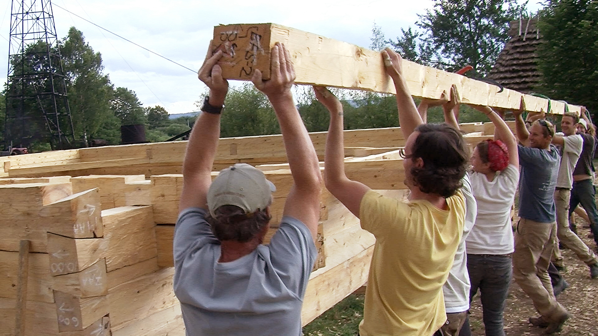 Still 15: At the Sanok workshop in 2011, students and professionals lift a dimensional timber on to the log wall. 