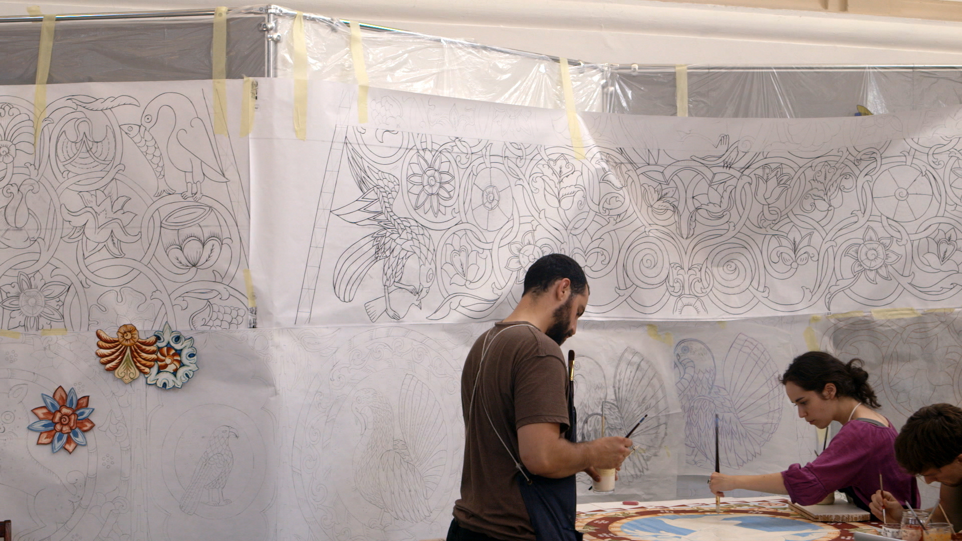 Still 28: Jason Loik and Evelyn Tauben painting the backward facing deer in front of the tracings for the south dome.