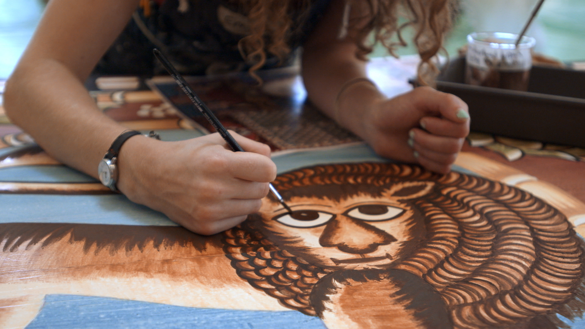 Still 36: Emily White paints the lion for the east dome panel.
