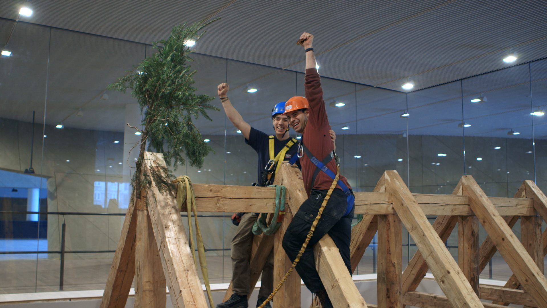 Still 44: Jason Loik and Jacob Jensen celebrate the raising of the roof by placing an evergreen tree at the top.