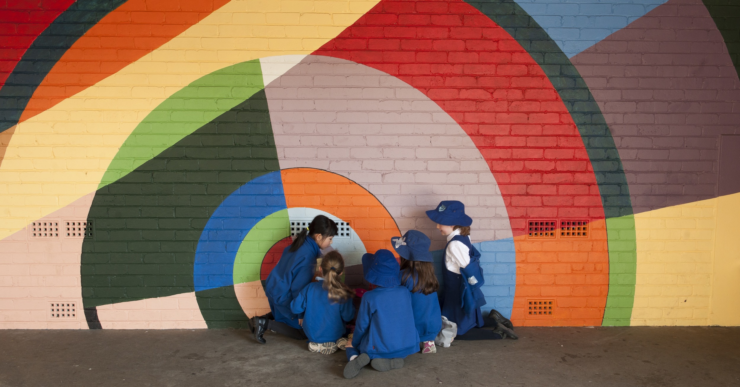 Artamon Public School, Sydney 2013 The Principal of Artarmon Public School commissioned a series of four murals within the school grounds. This colourful, circular piece pictured is situated in what was a dark, covered courtyard near the water fountains. The aim was obviously to brighten the space for the students, but it has had an added impact in providing a historical context for the school grounds as a whole. The inspiration was the work of French artist Sonia Delaunay who was one of the first avant garde female painters at the very dawn of the Art Deco movement. It seemed a fitting tribute to the school itself which was founded in 1928 - the same time as Delaunay’s dynamic work was in its heyday. (Photograph: Niki Hughes Photography) The second piece featured here, 'the hopscotch mural', is a new take on one of Hugues' French murals, this time drawing heavily on both the palette and the energy evoked by the graphic abstract. The hopscotch piece breathes new and colourful life into our conception of a classic school yard game, and has proven to be hugely appealing to both children and adults alike.