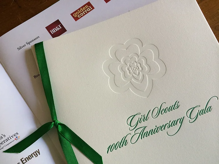 Close up of Girl Scouts 100th Anniversary Gala invitation with event program