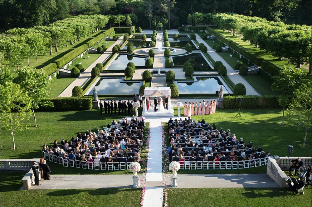 Aerial view of elegant outdoor wedding ceremony set in formal garden estate
