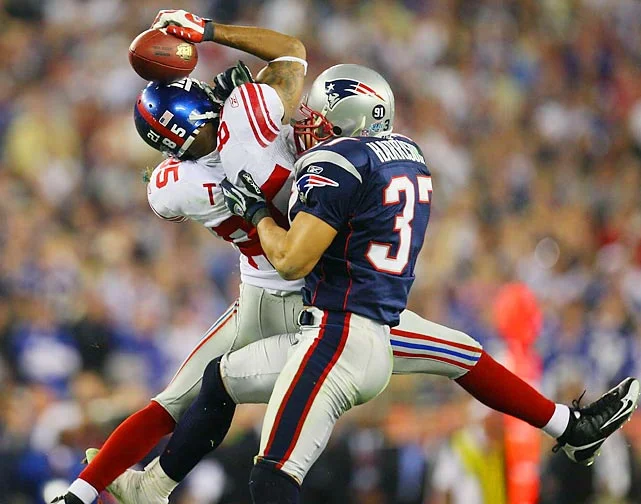 New York Giants wide receiver David Tyree somehow manages to hang on to the catch by pinning the ball against his helmet as New England Patriots safety Rodney Harrison hits him late in the fourth quarter. Tyree also caught a touchdown pass earlier in the fourth quarter that helped the Giants to their 17-14 victory.