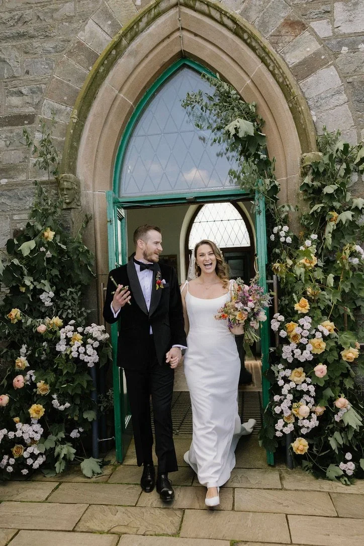 Romantic floral installation around Irish church doors with soft textures and movement.webp